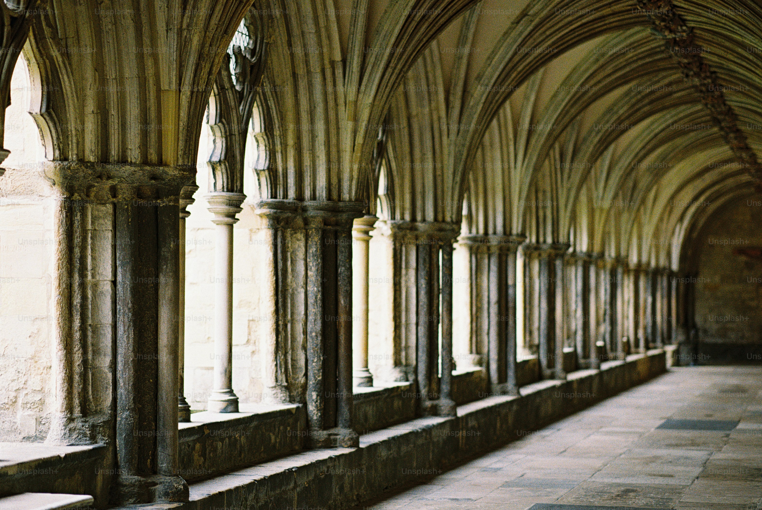 Un claustro de piedra con columnas arqueadas y techo abovedado en una catedral