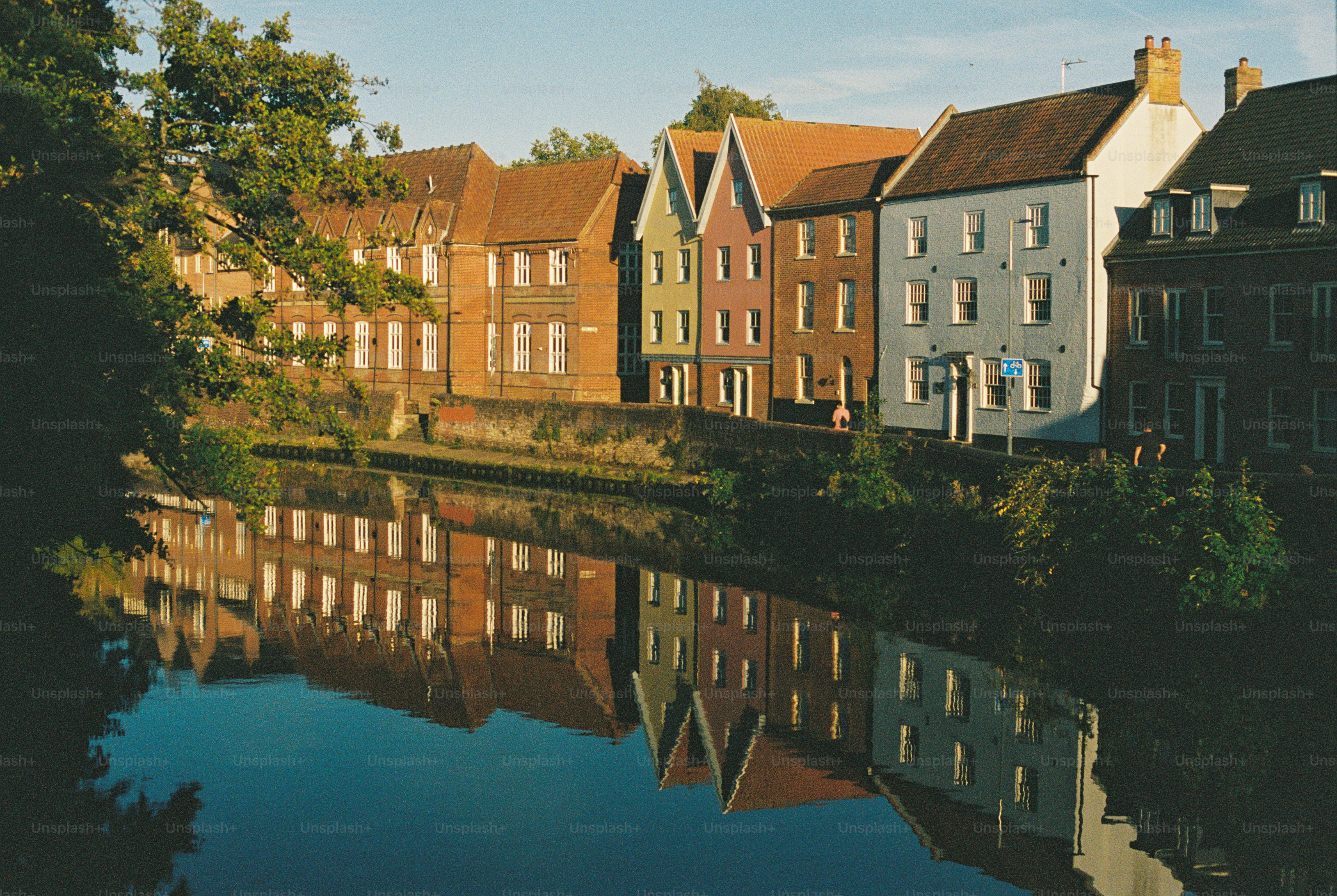Colorful historic houses reflected in the calm water of a canal at golden hour