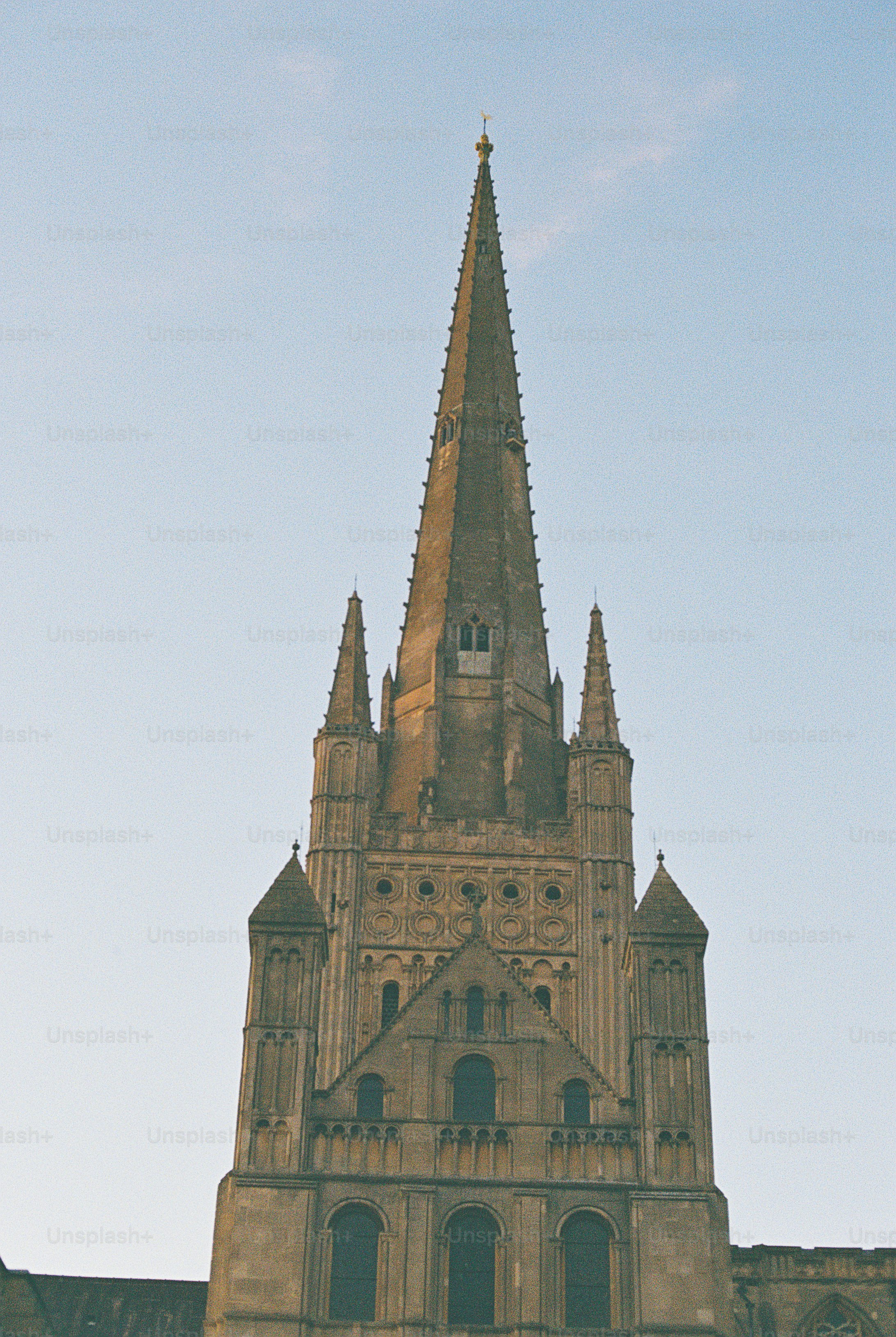 A tall stone church spire with gothic architectural details against a clear sky