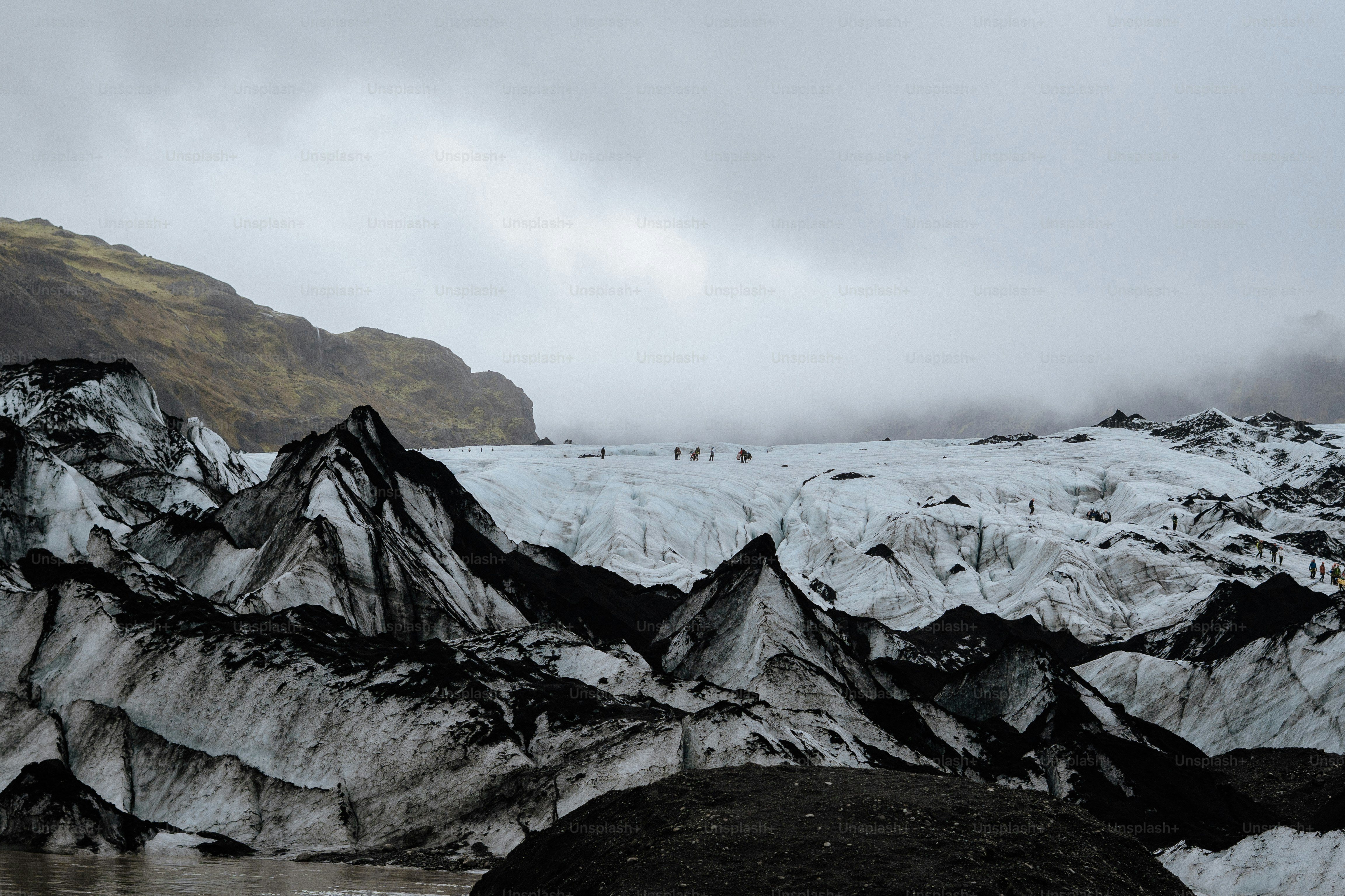 A group of people hiking across a vast glacier with black volcanic rock