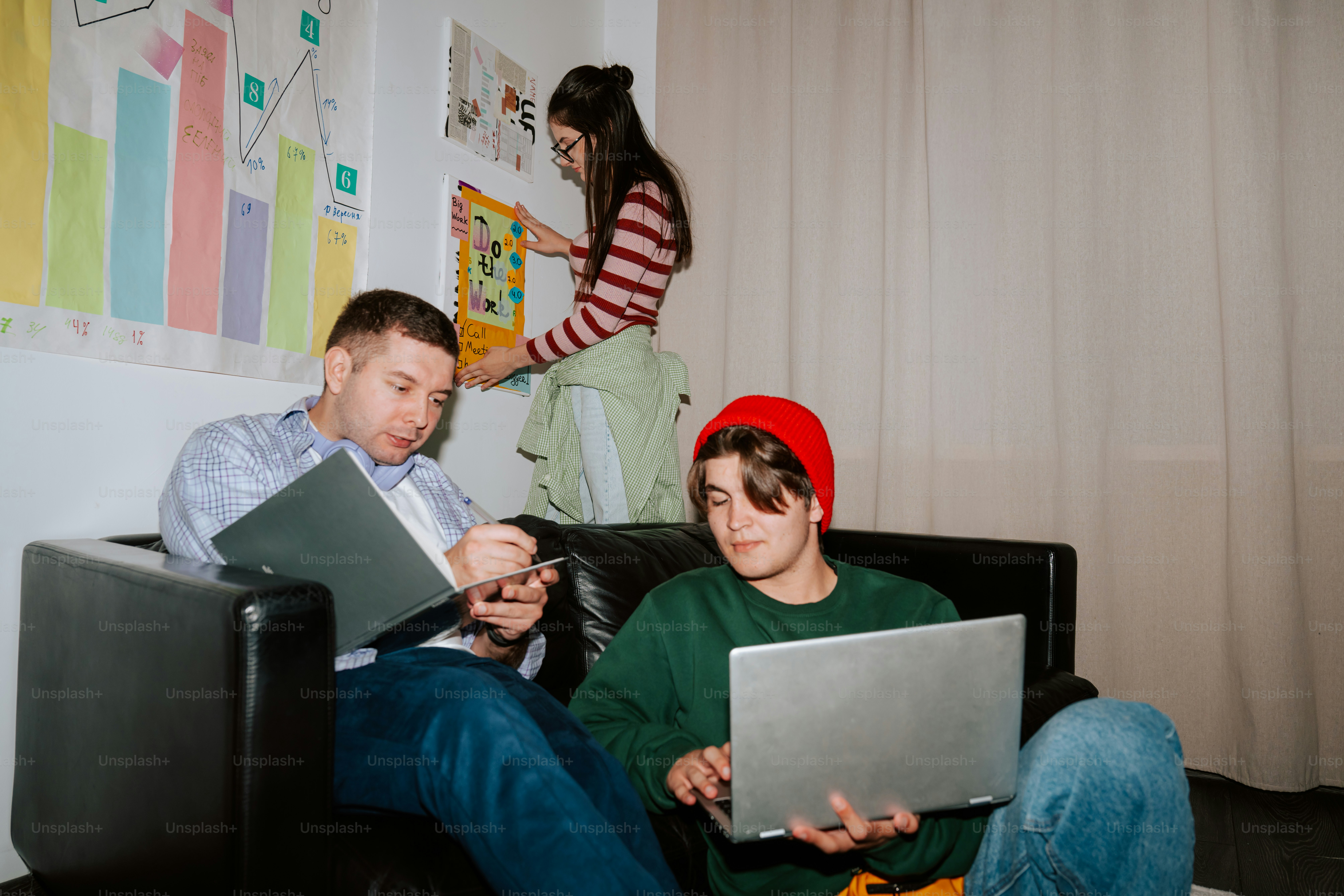 Three people working in a room with a chart on the wall