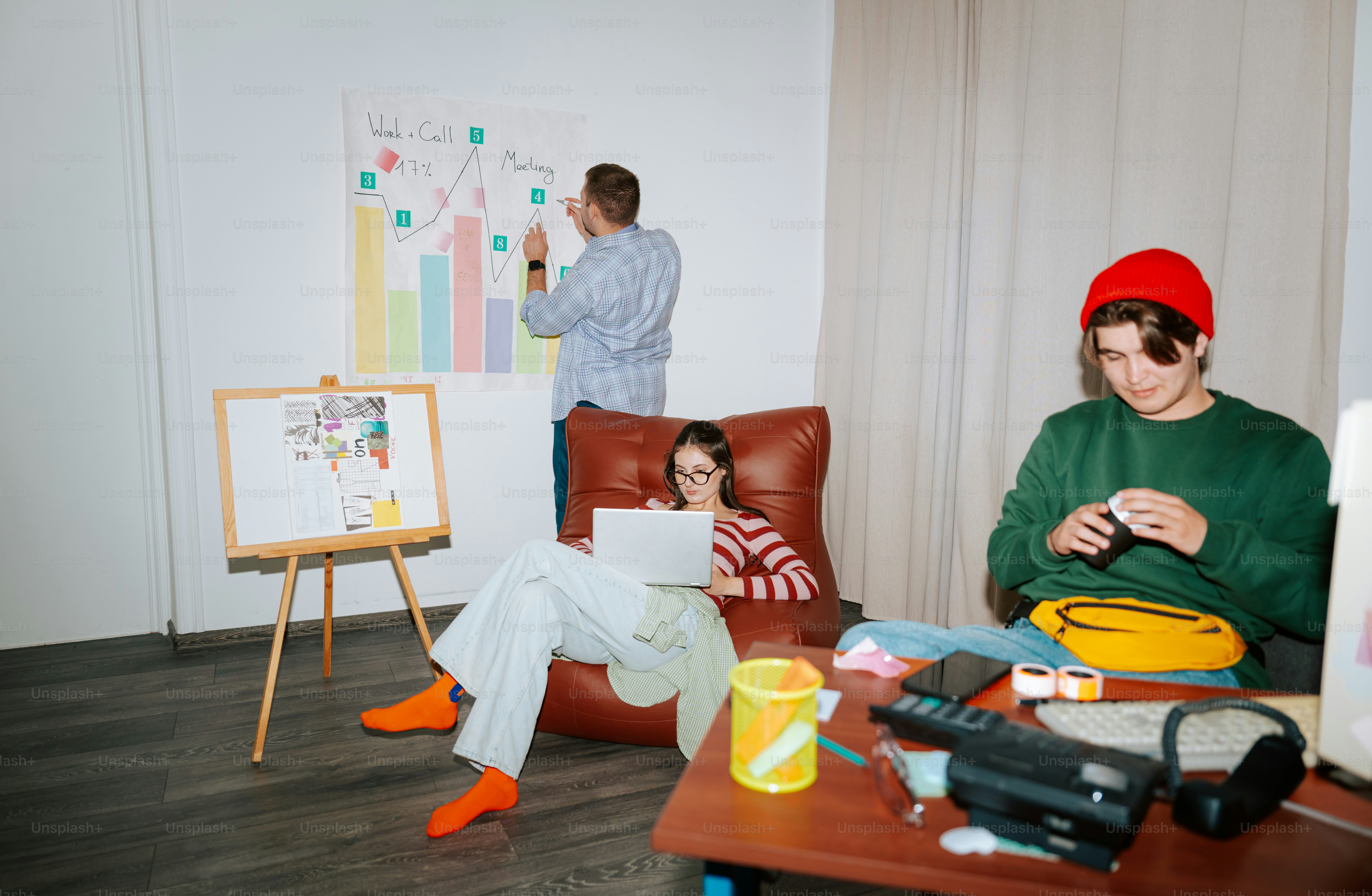 A person writing on a chart while others work in a casual office