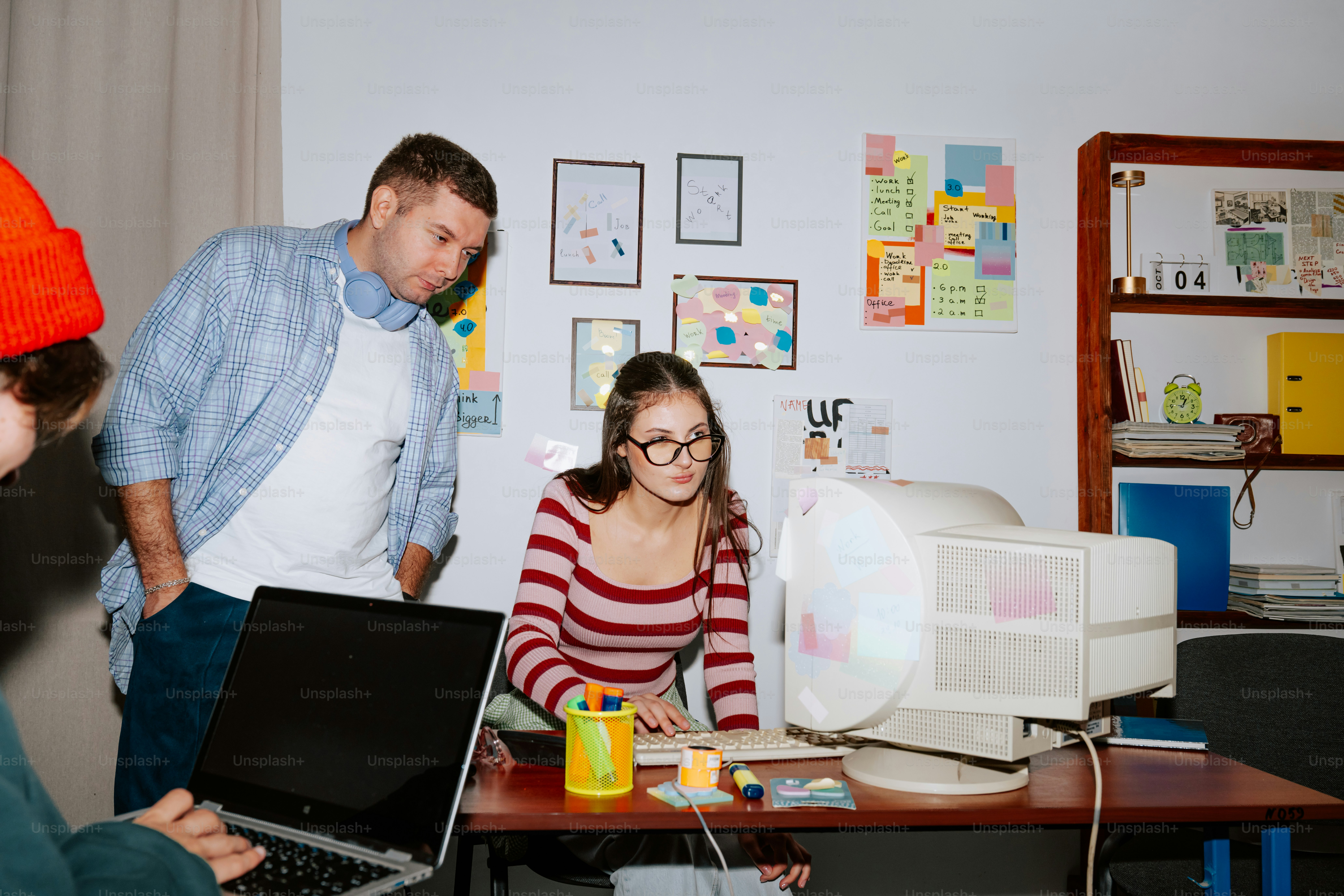 A woman and a man working at a desk with a computer and laptop