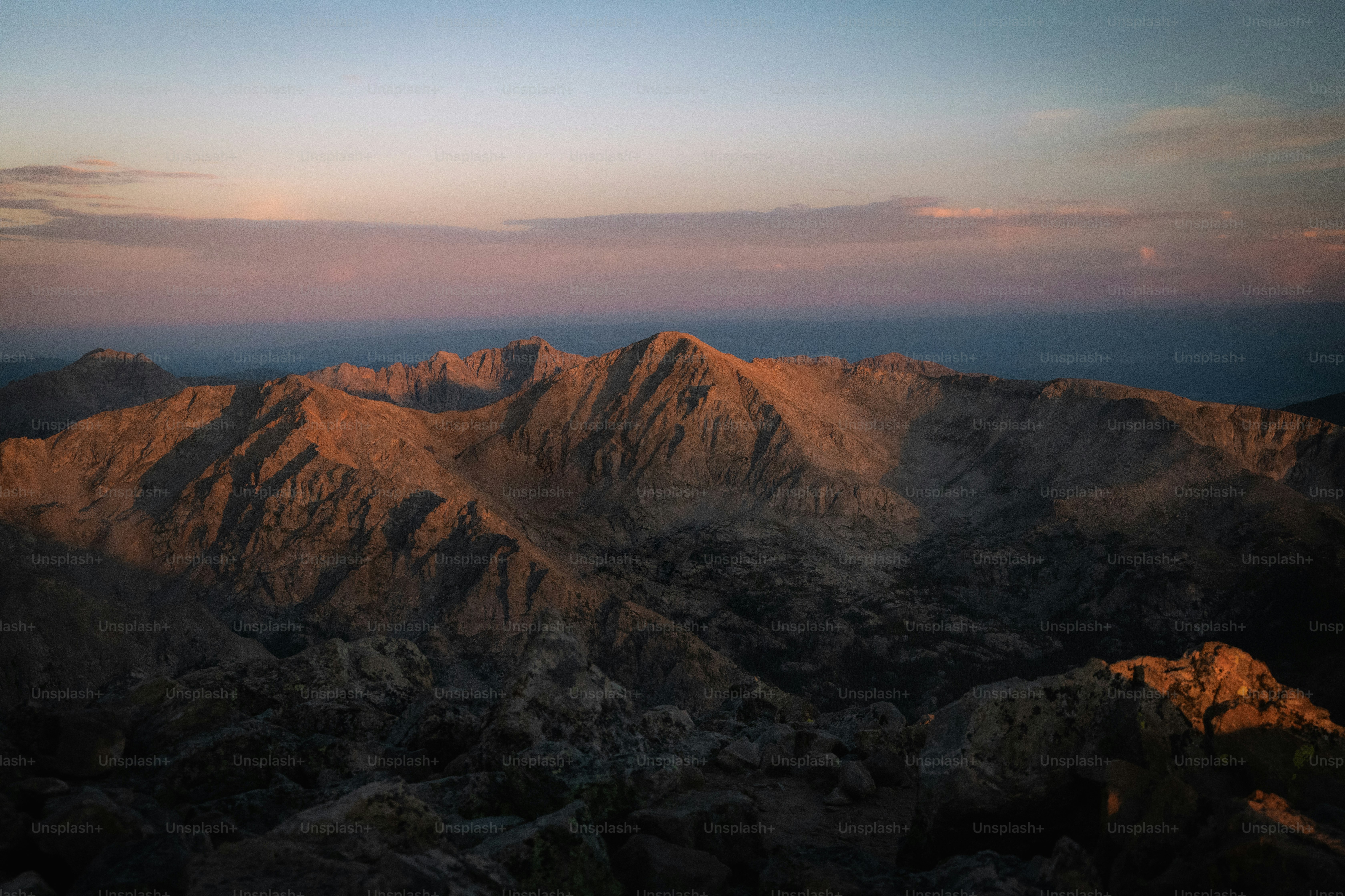 Rugged mountain peaks illuminated by low golden light under a soft purple sky