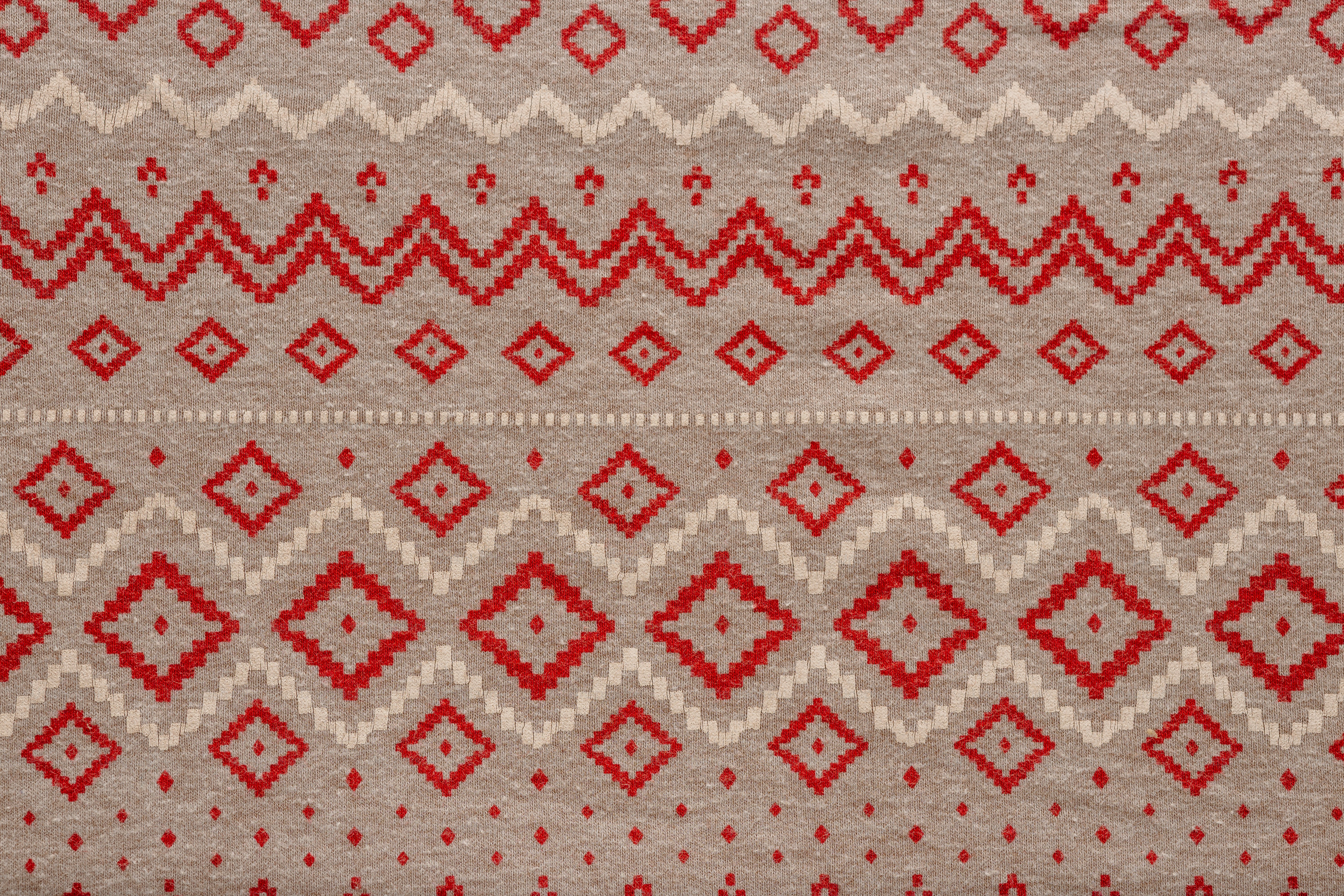 A beige fabric with a repeating pattern of red diamonds and zigzag lines
