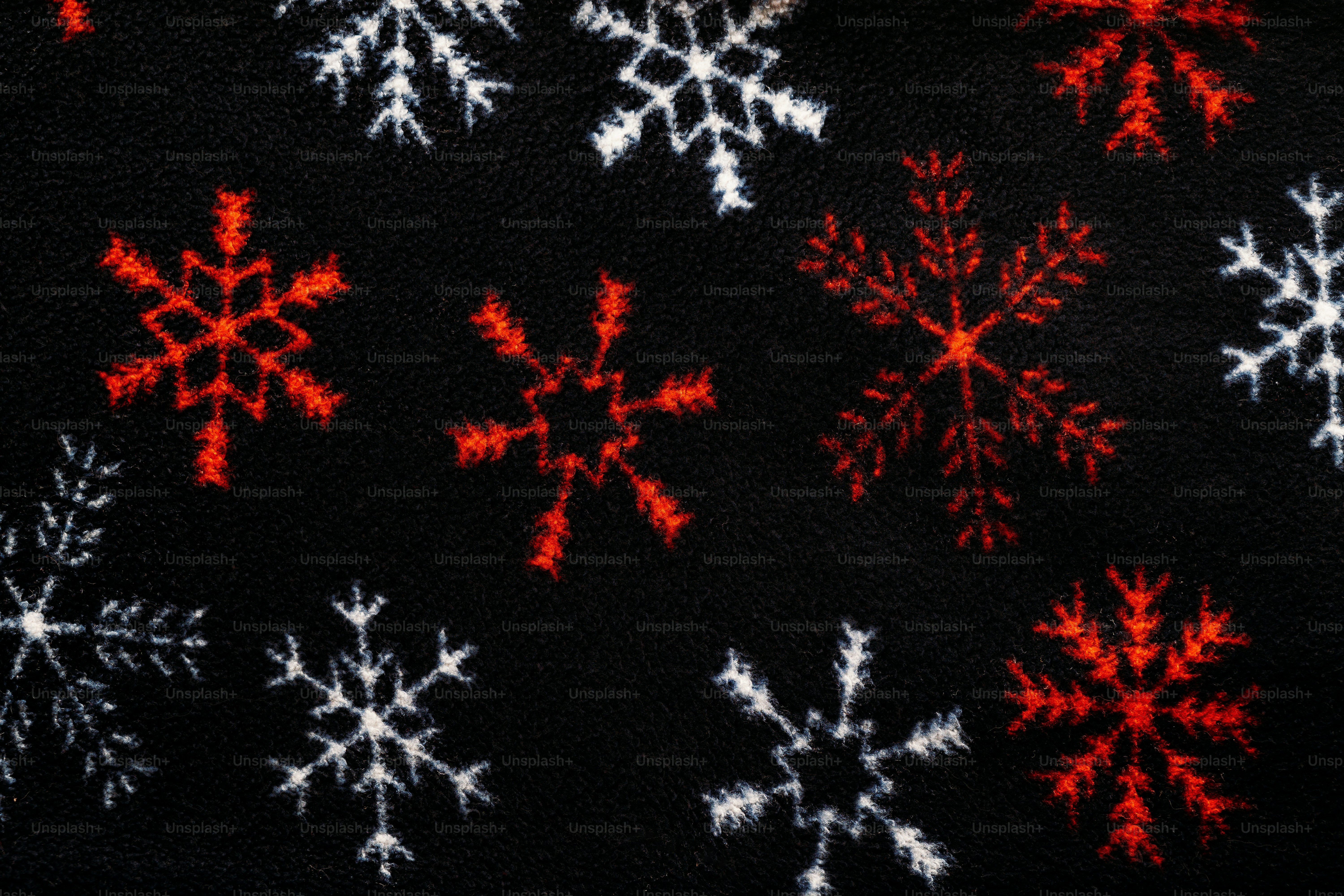 Red and white snowflake patterns on a black fabric background