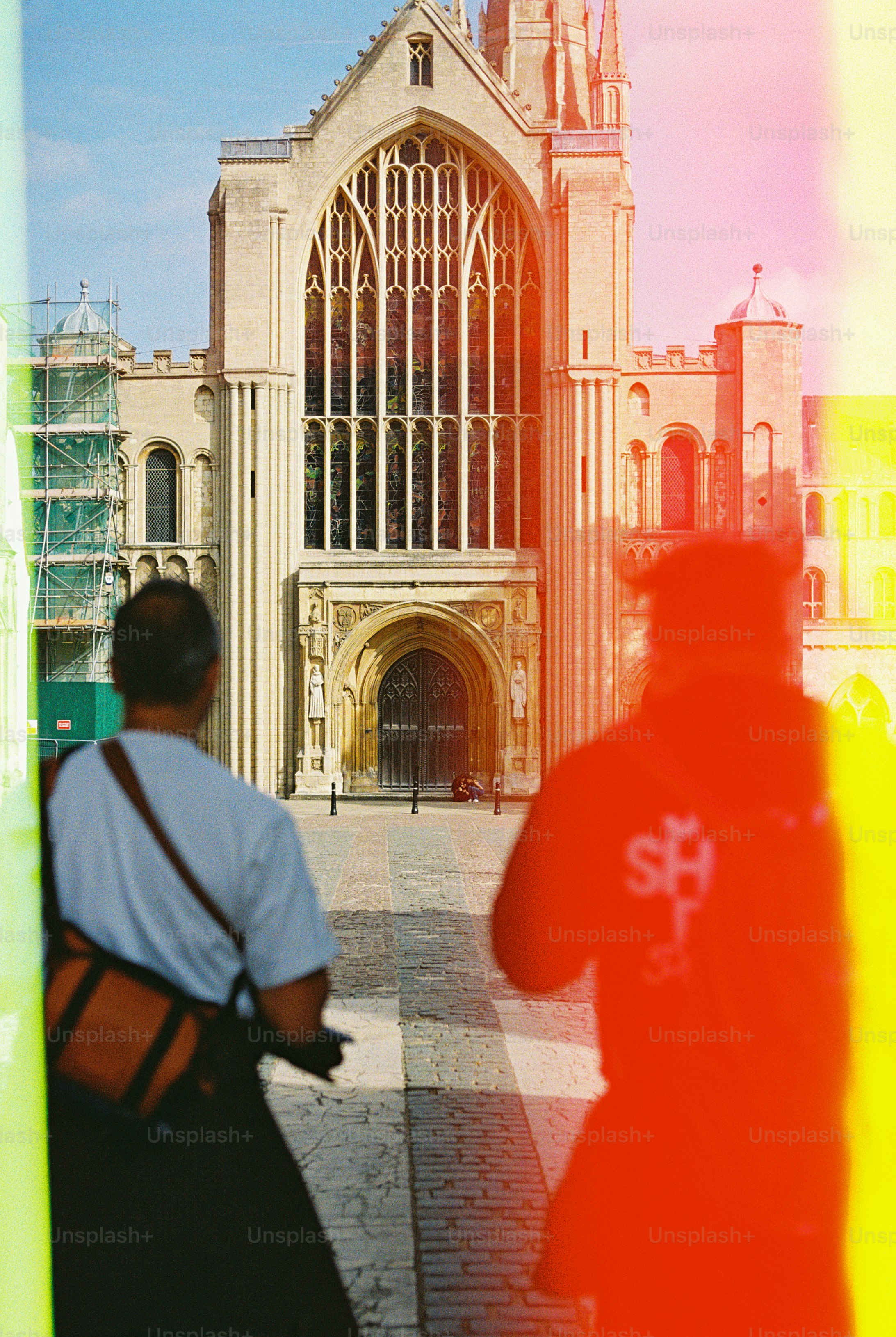 Two people walking toward a large stone cathedral with stained glass windows