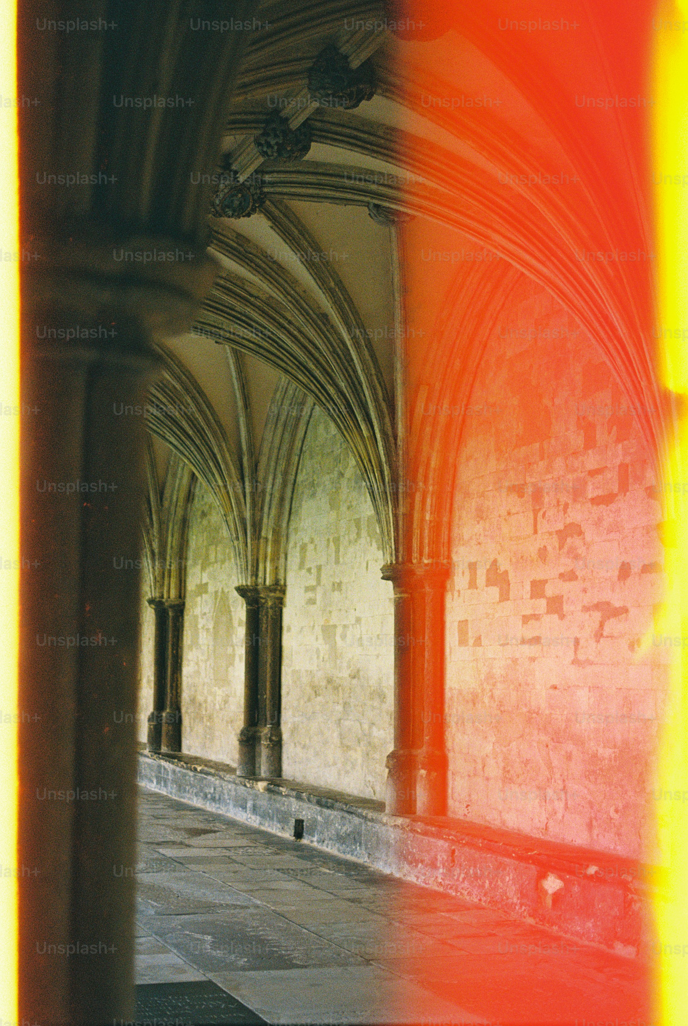 Stone arches and columns in a cloister with a bright red light leak