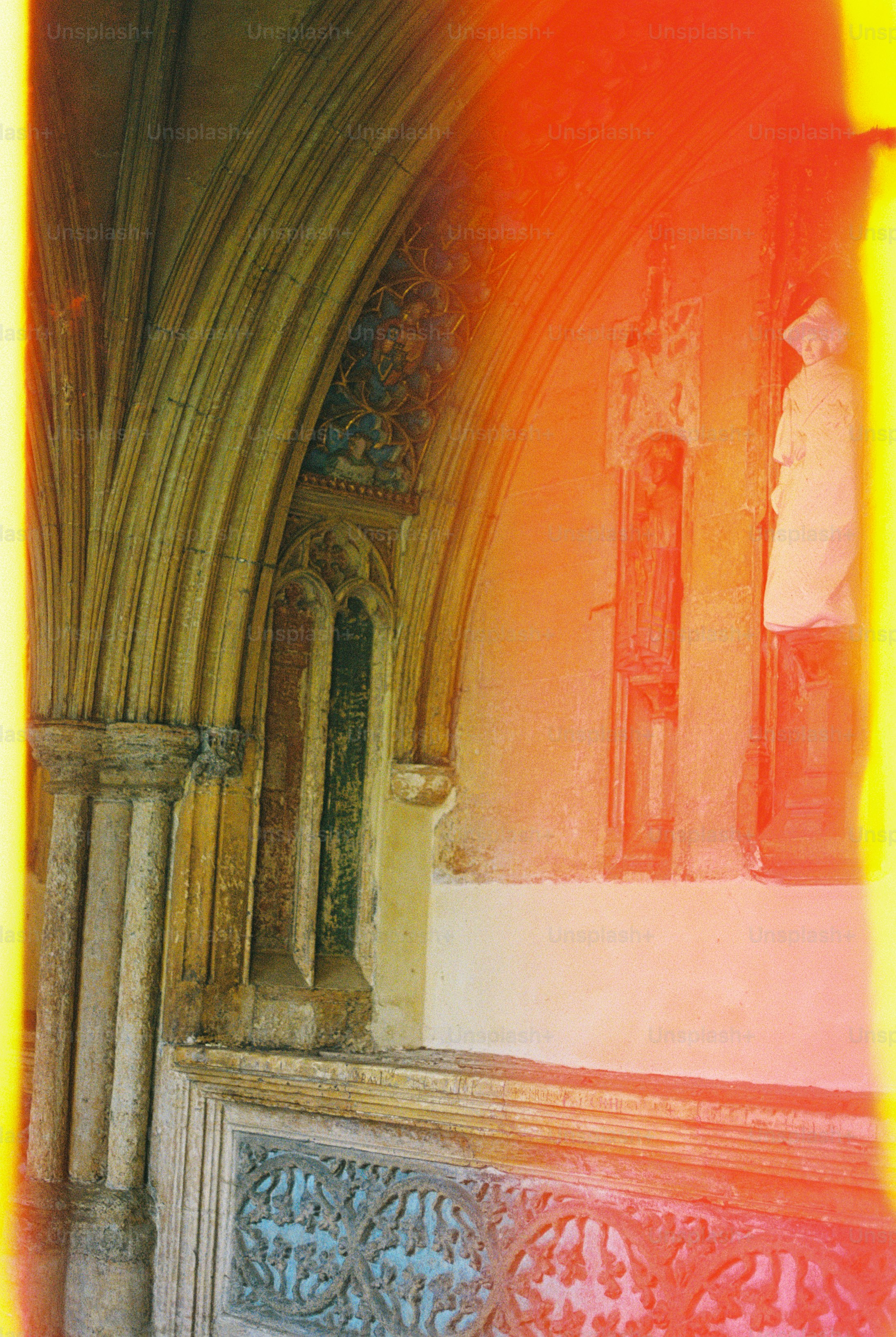 Stone archway with carved statues and ornate relief patterns under a bright light leak