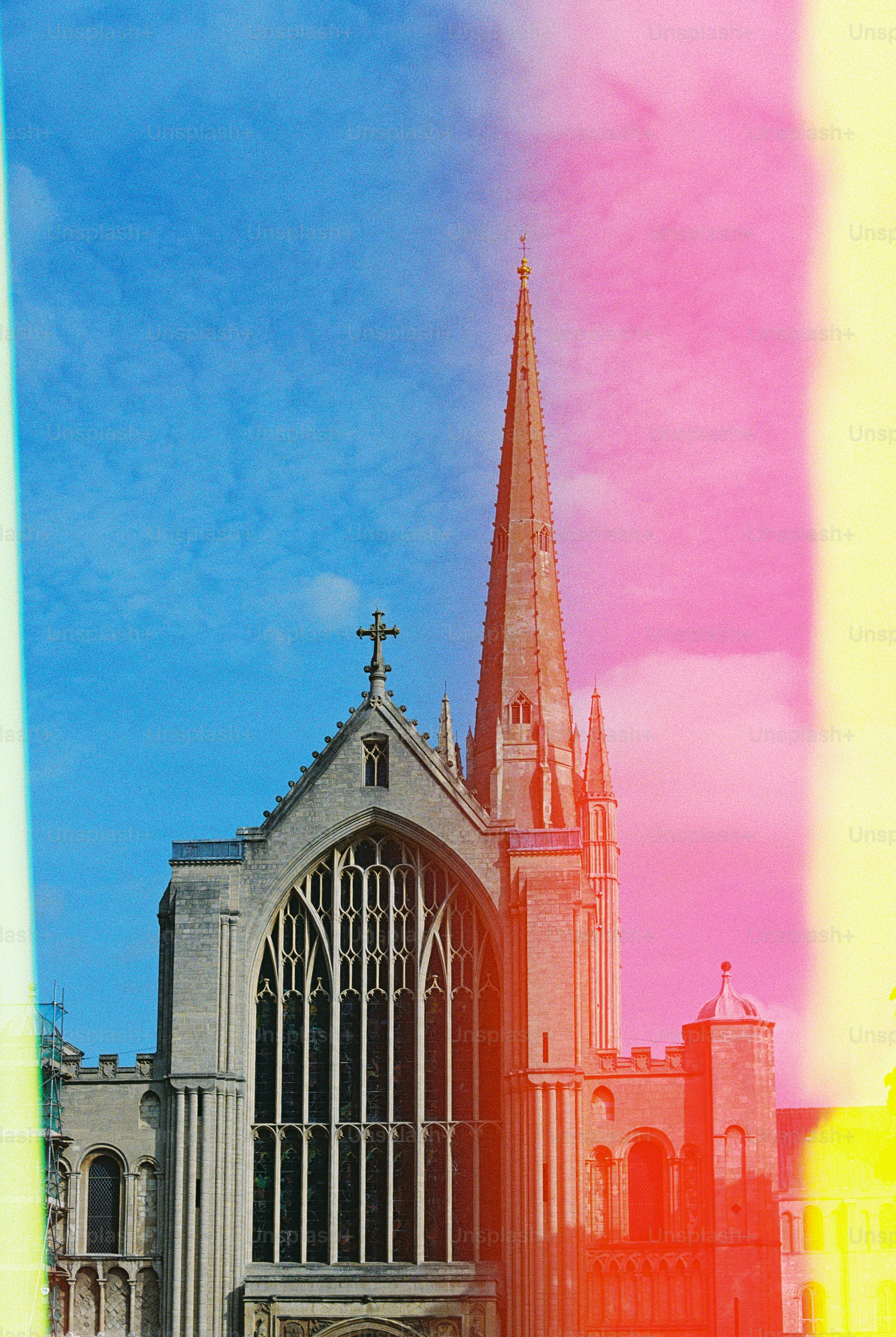 A stone cathedral with a tall spire against a blue sky with light leaks