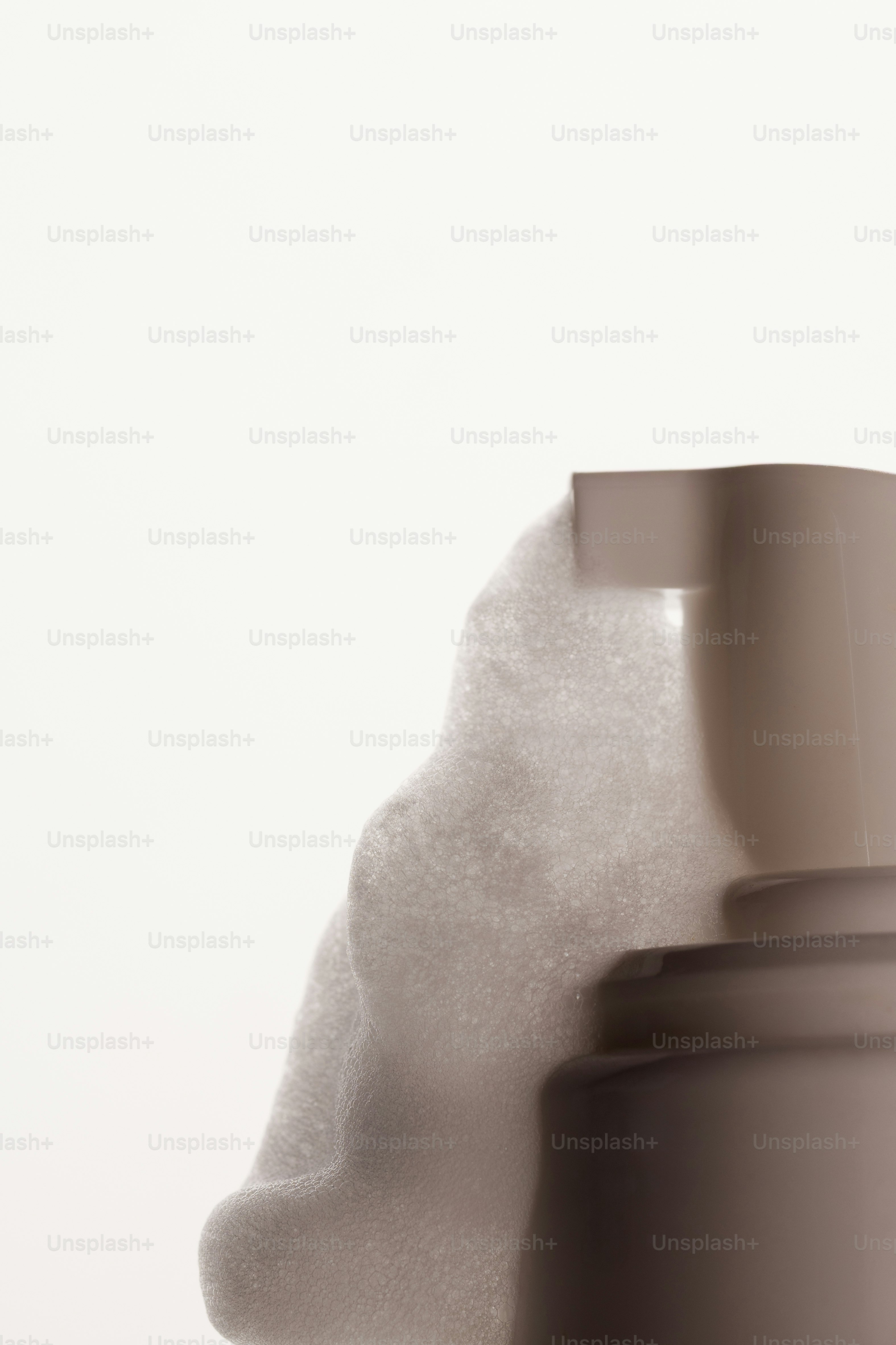White cleansing foam dripping from a pump bottle against a light background
