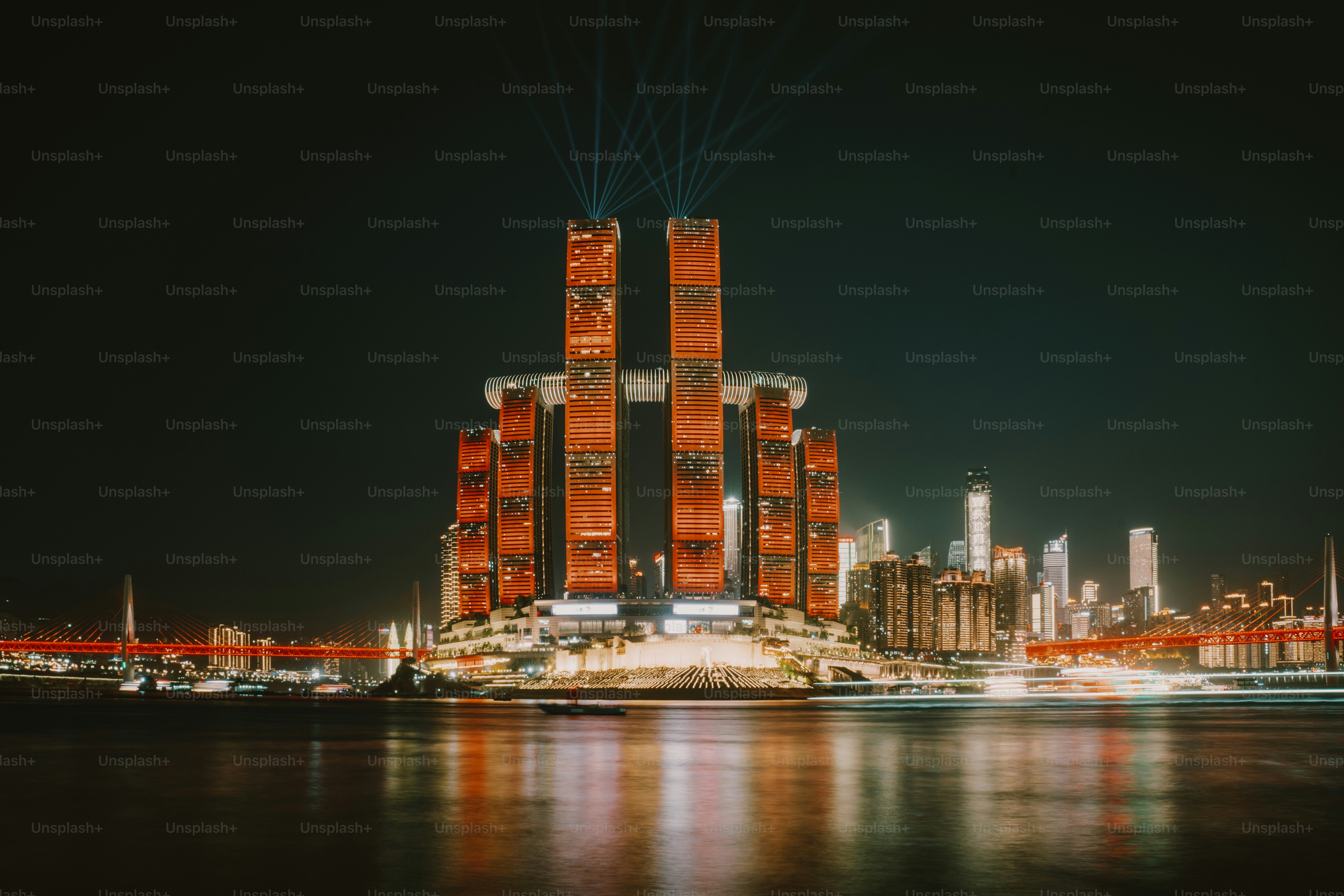 The Raffles City Chongqing complex illuminated at night with light beams over the Yangtze River