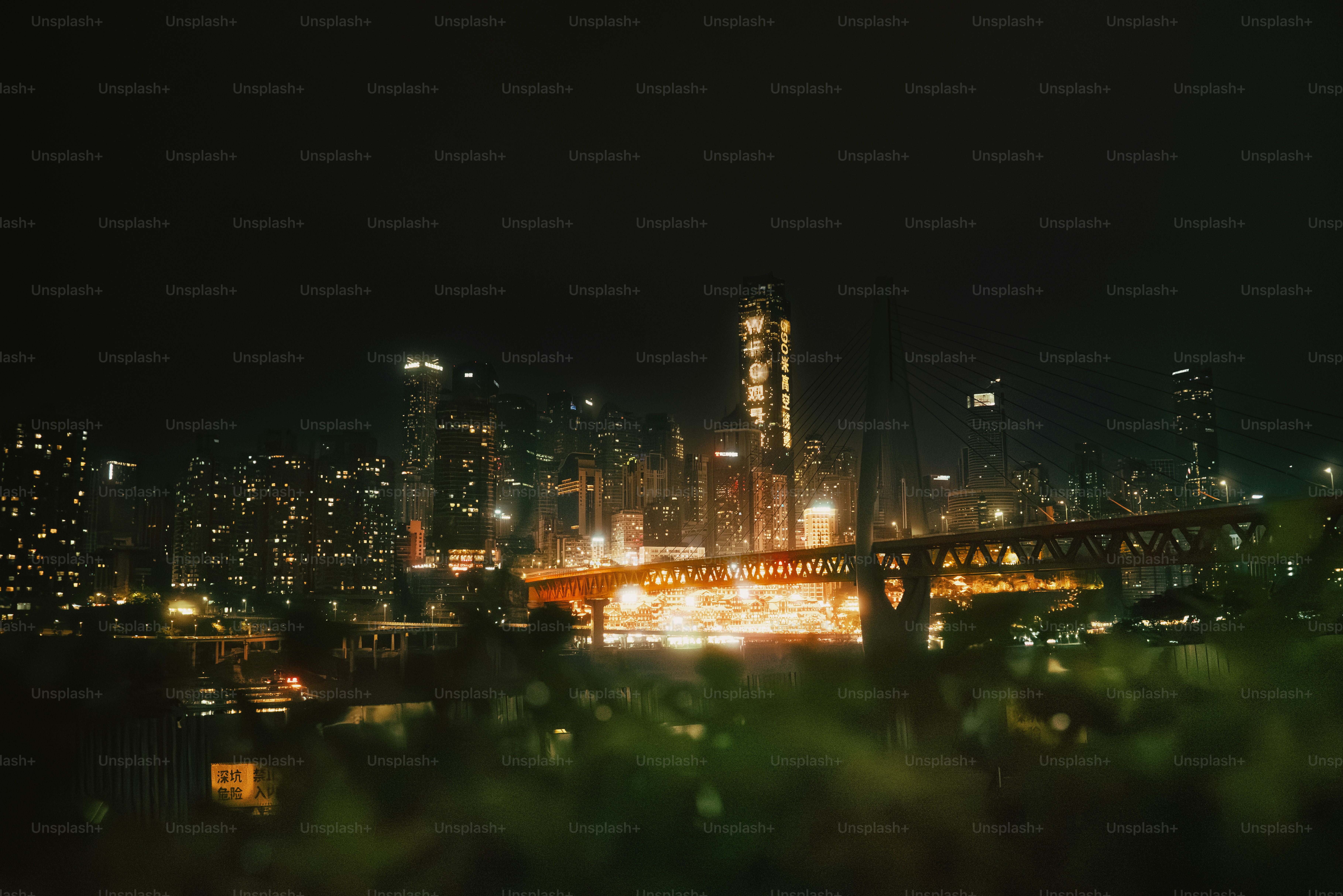 The illuminated skyline of Chongqing at night with a bridge crossing the river