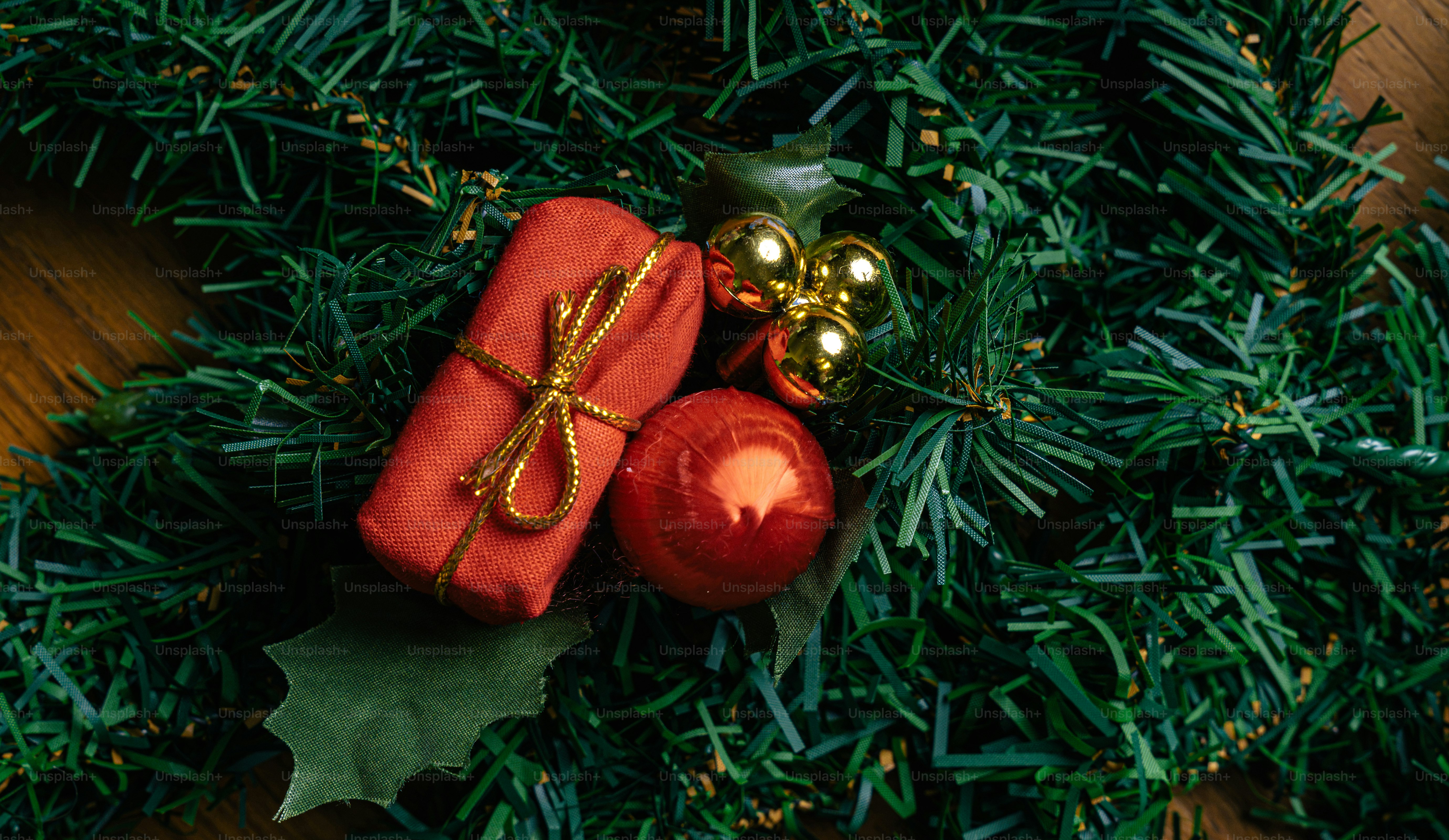A red gift box and a red ornament on green artificial pine branches