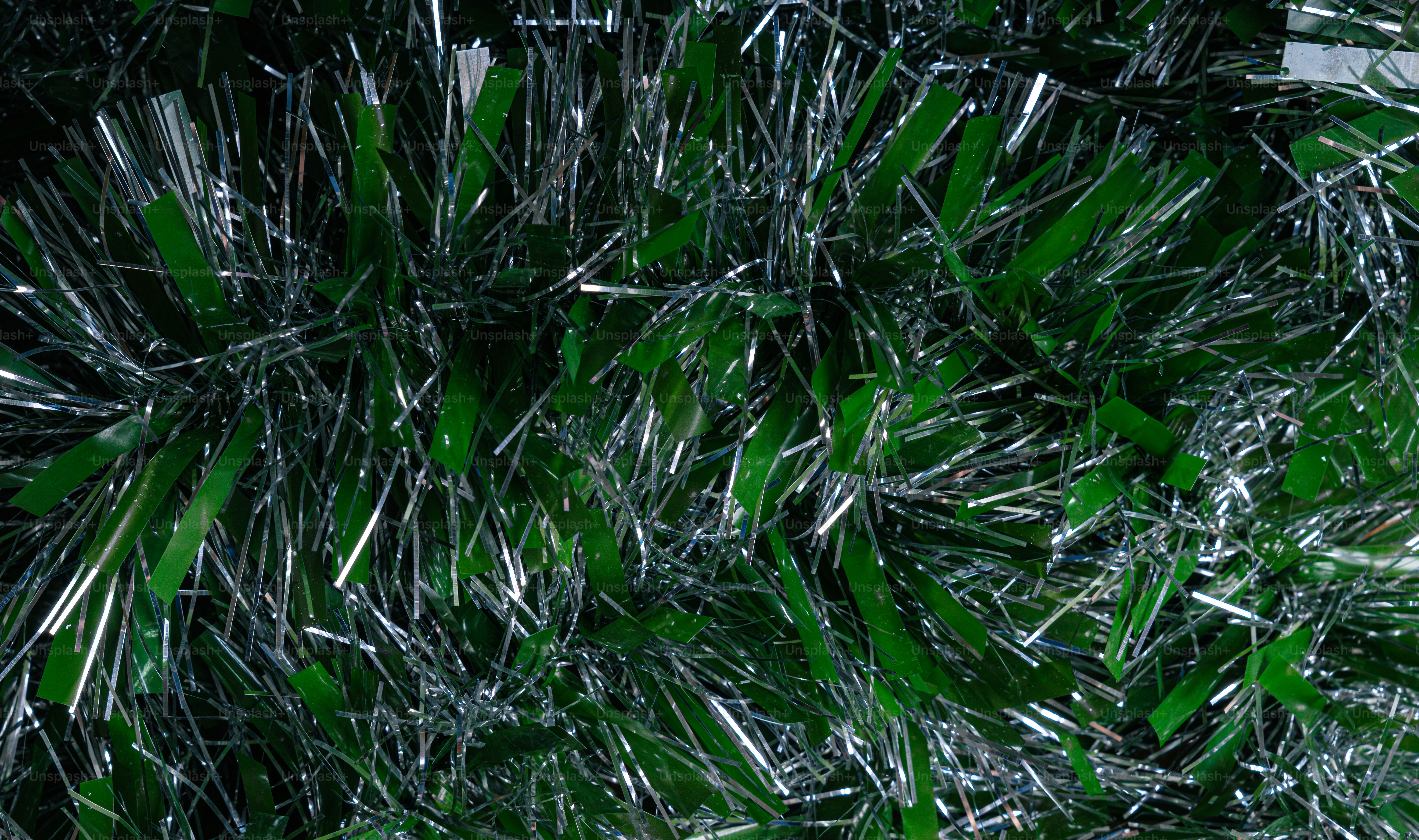 Green and silver tinsel strands forming a dense festive texture