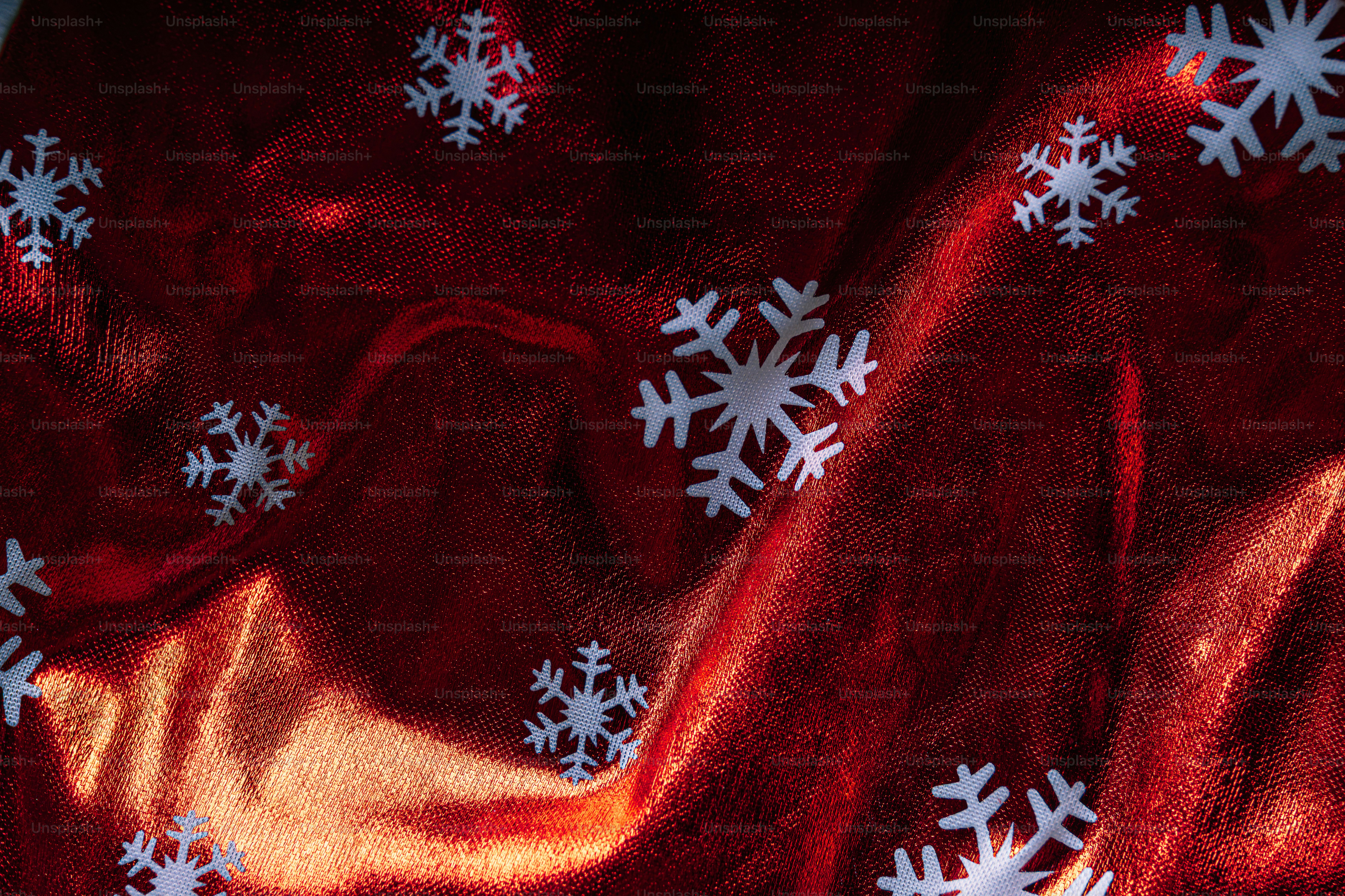White snowflake cutouts scattered across a shimmering red and gold fabric