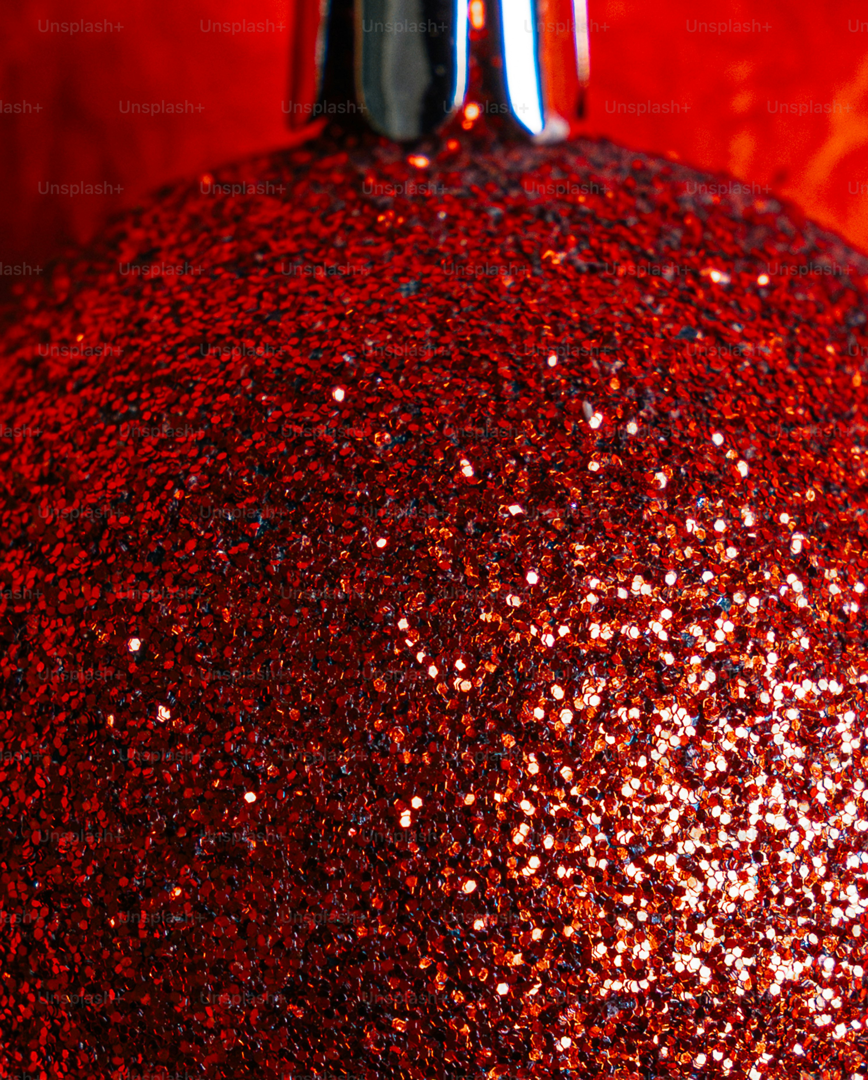 A close-up of a red glittery Christmas ornament with a silver cap
