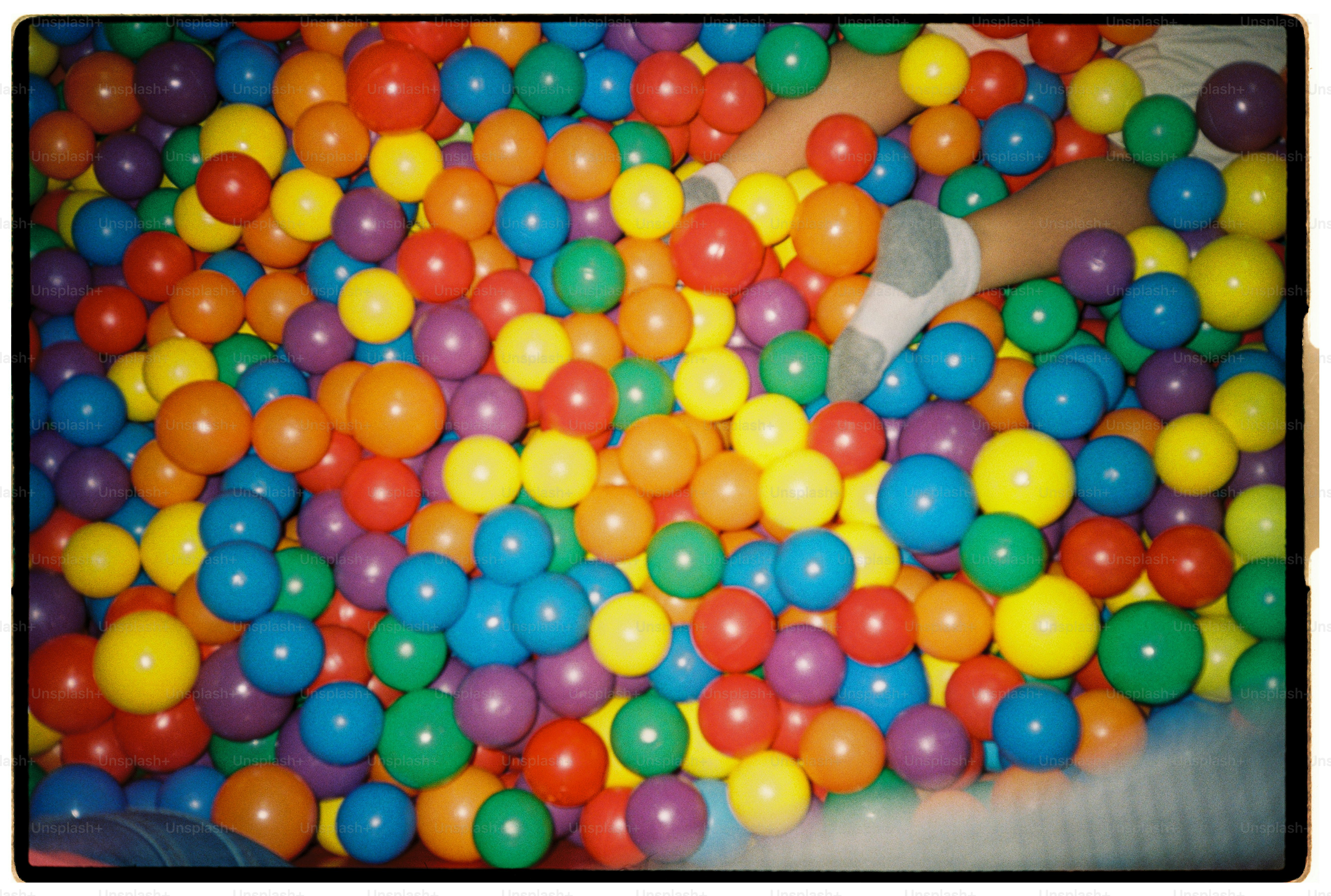 A person wearing grey socks in a colorful plastic ball pit
