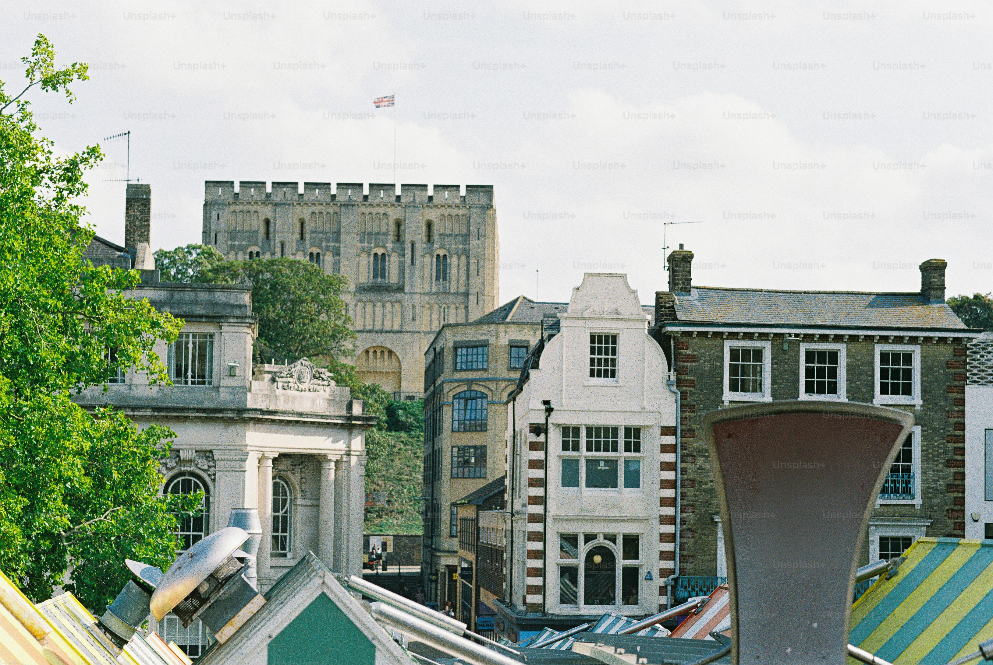 The historic Norwich Castle overlooking traditional buildings and market stalls in Norwich