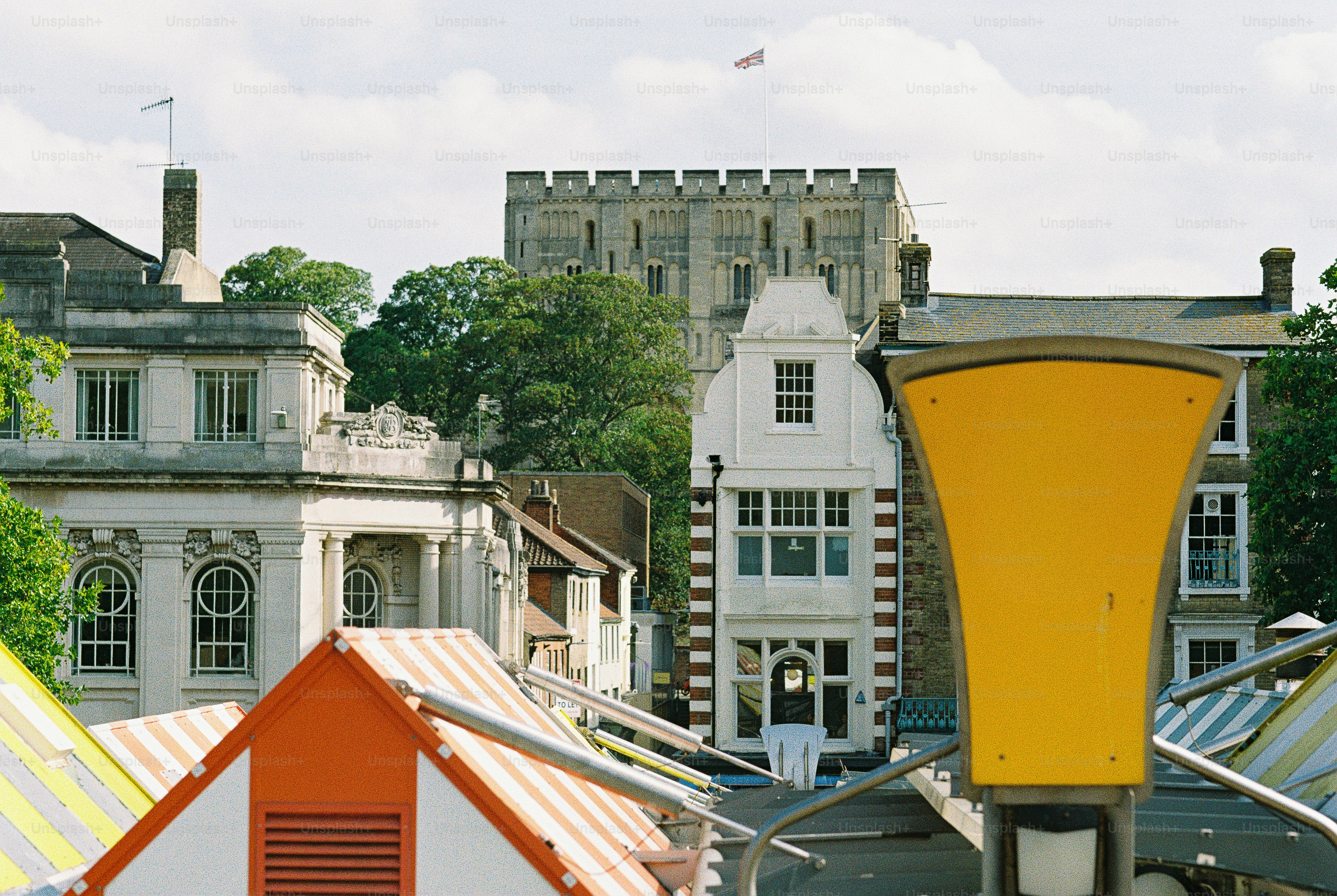 A view of Norwich Castle and historic buildings behind colorful market stalls