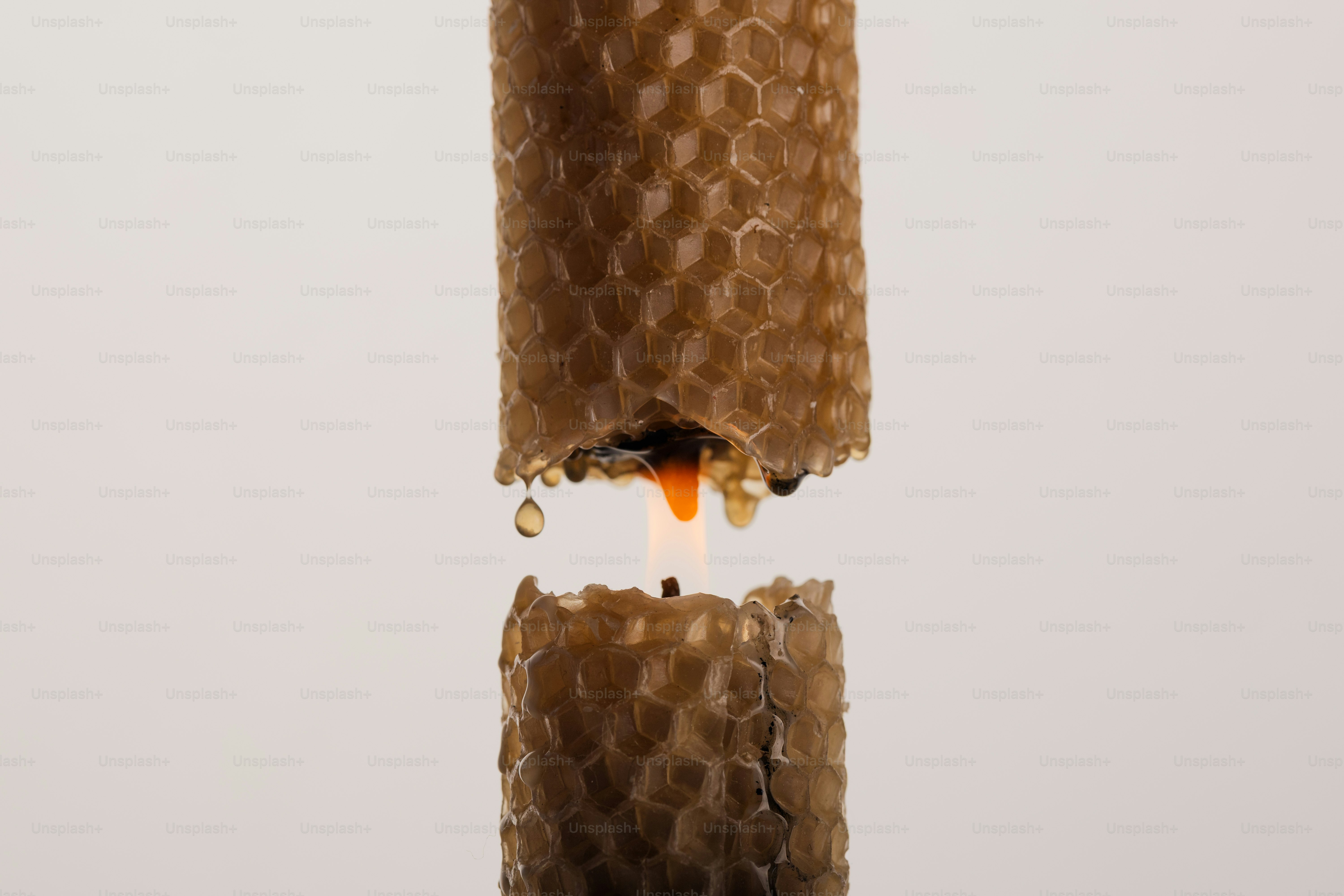 Burning beeswax candle with honeycomb texture - Photo on Unsplash+