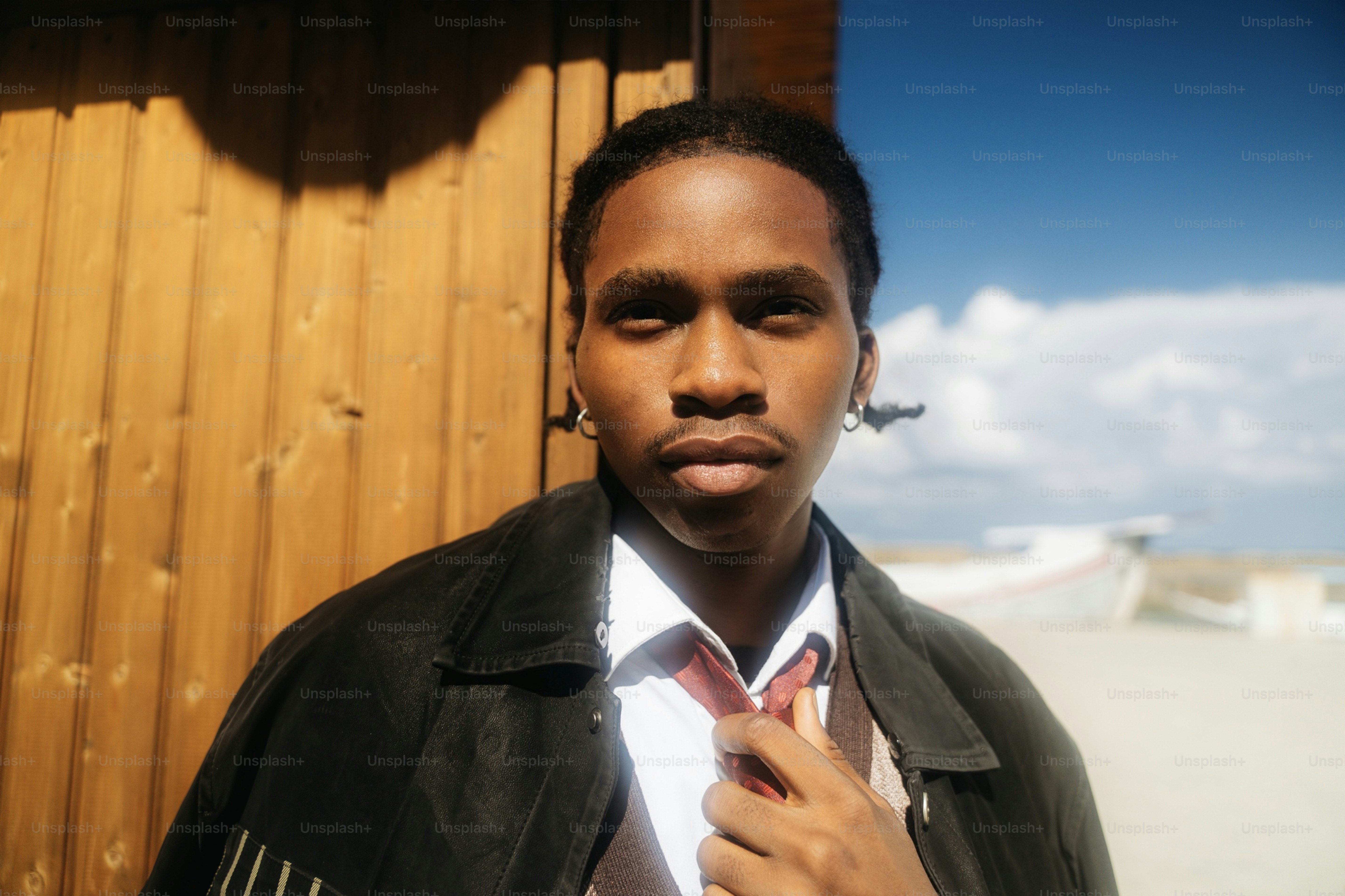 A young man in a white shirt and dark jacket adjusting his red tie