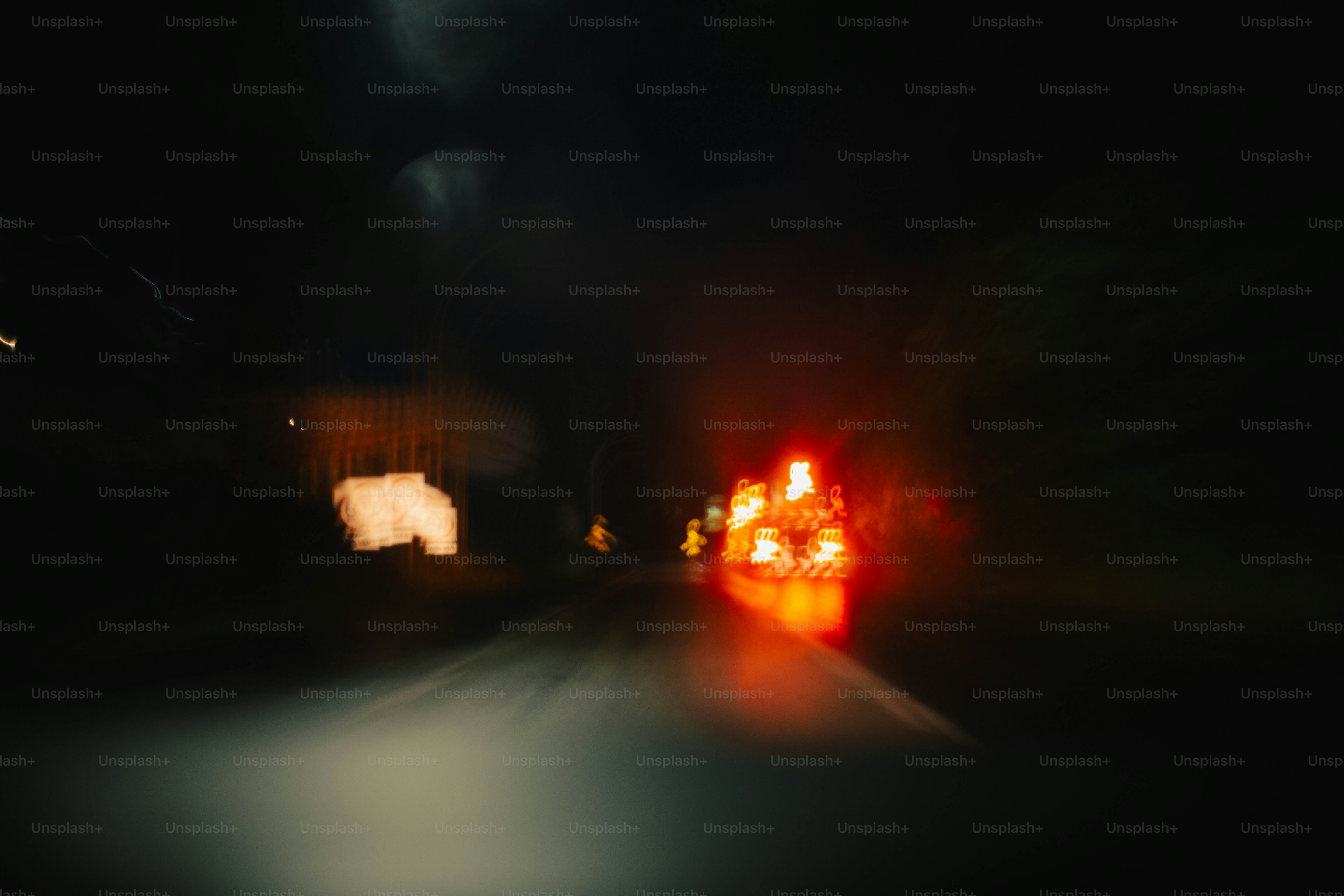 Blurred red and orange vehicle lights on a dark road at night
