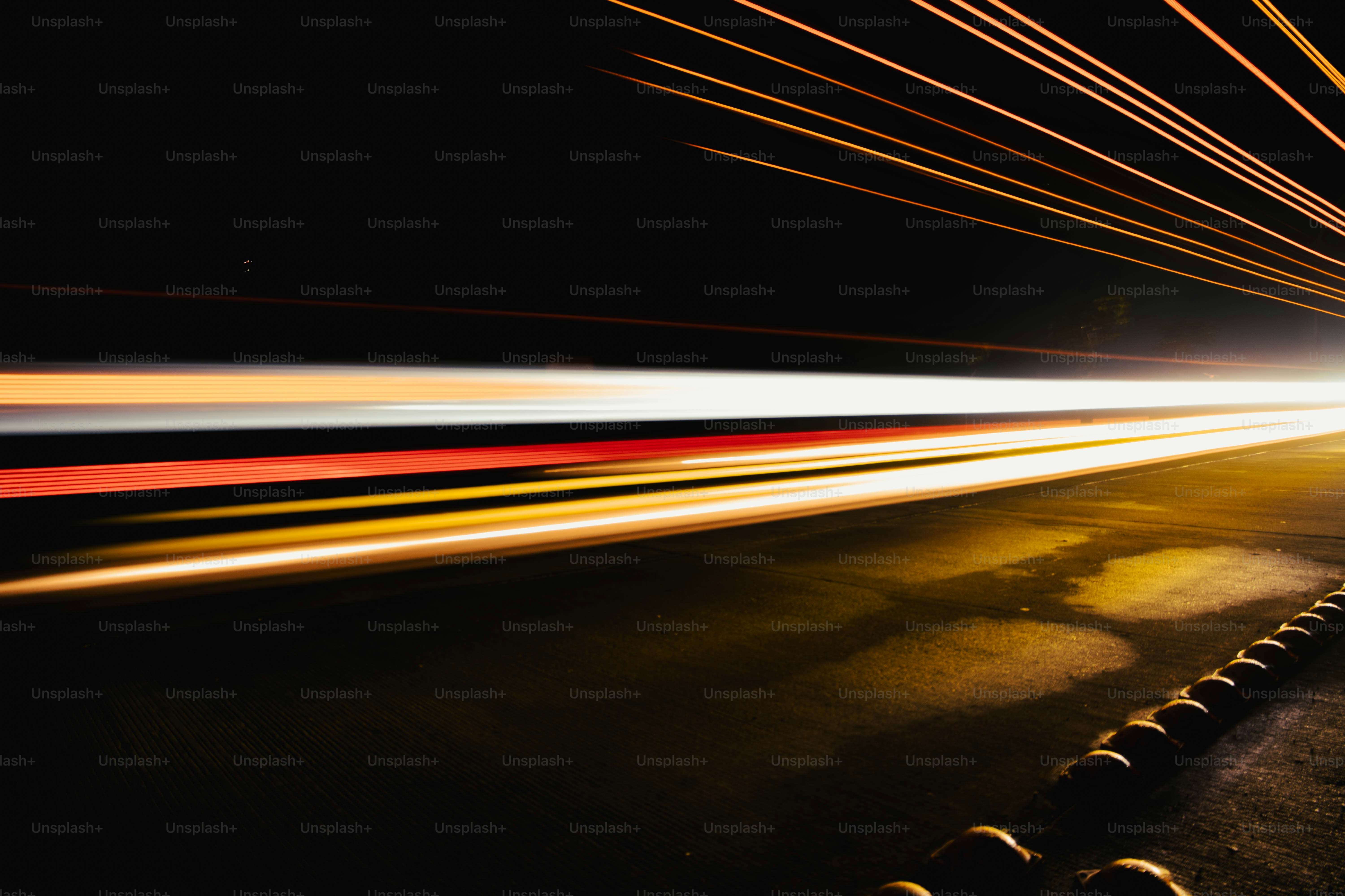 Long exposure light trails from passing vehicles on a dark road at night