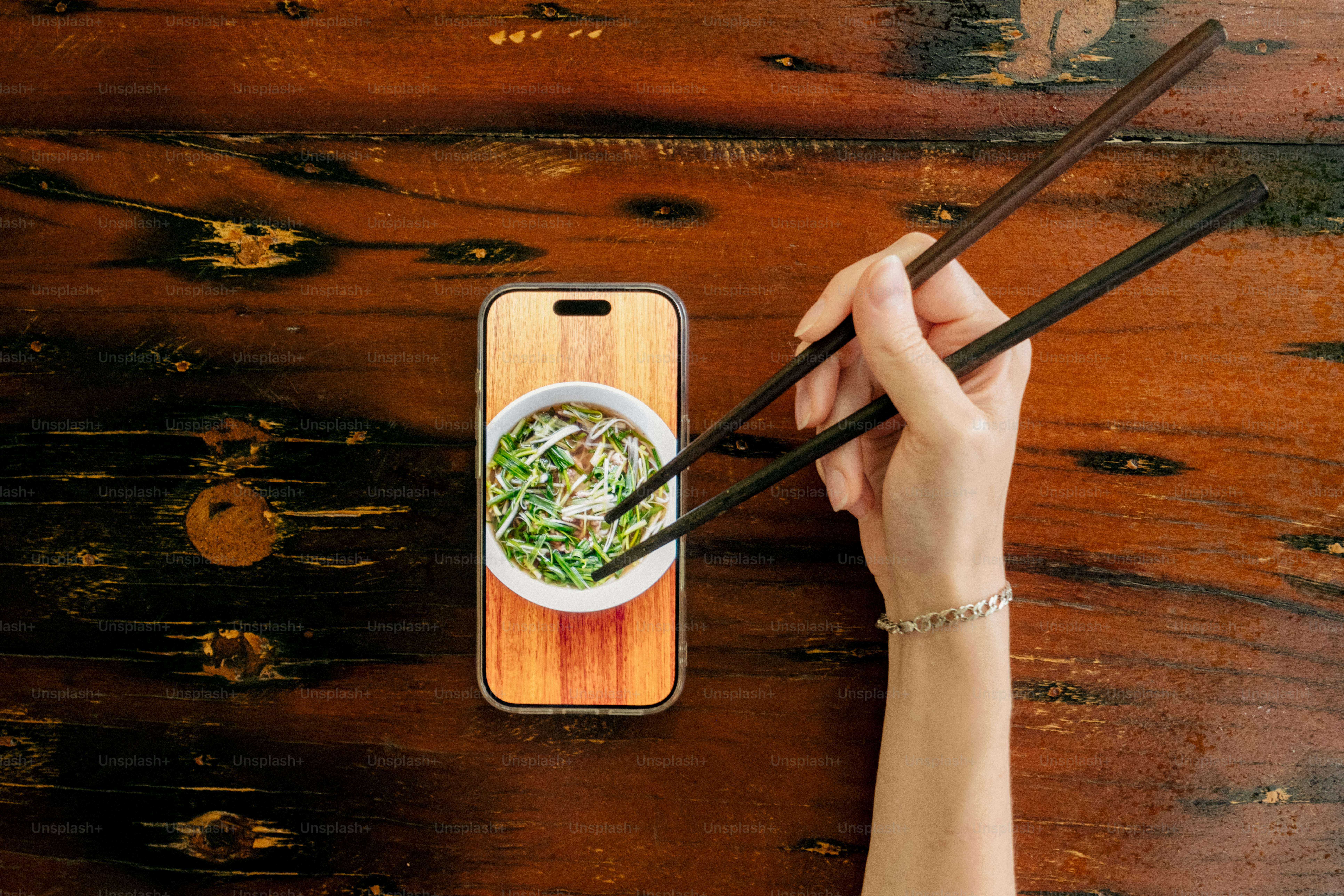 Hand holding chopsticks over smartphone screen - Photo on Unsplash+