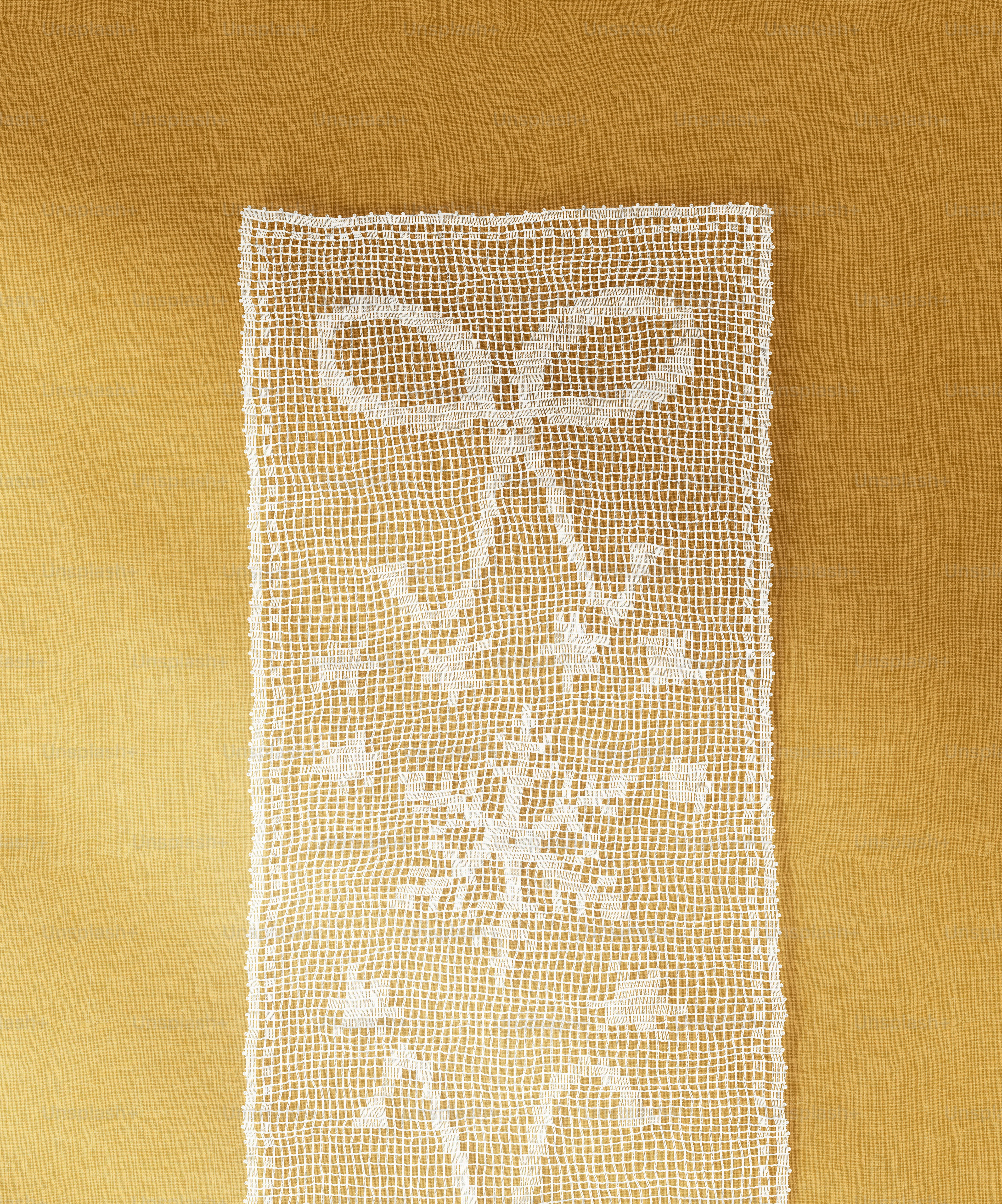 A white lace runner with a bow and snowflake pattern on a gold background