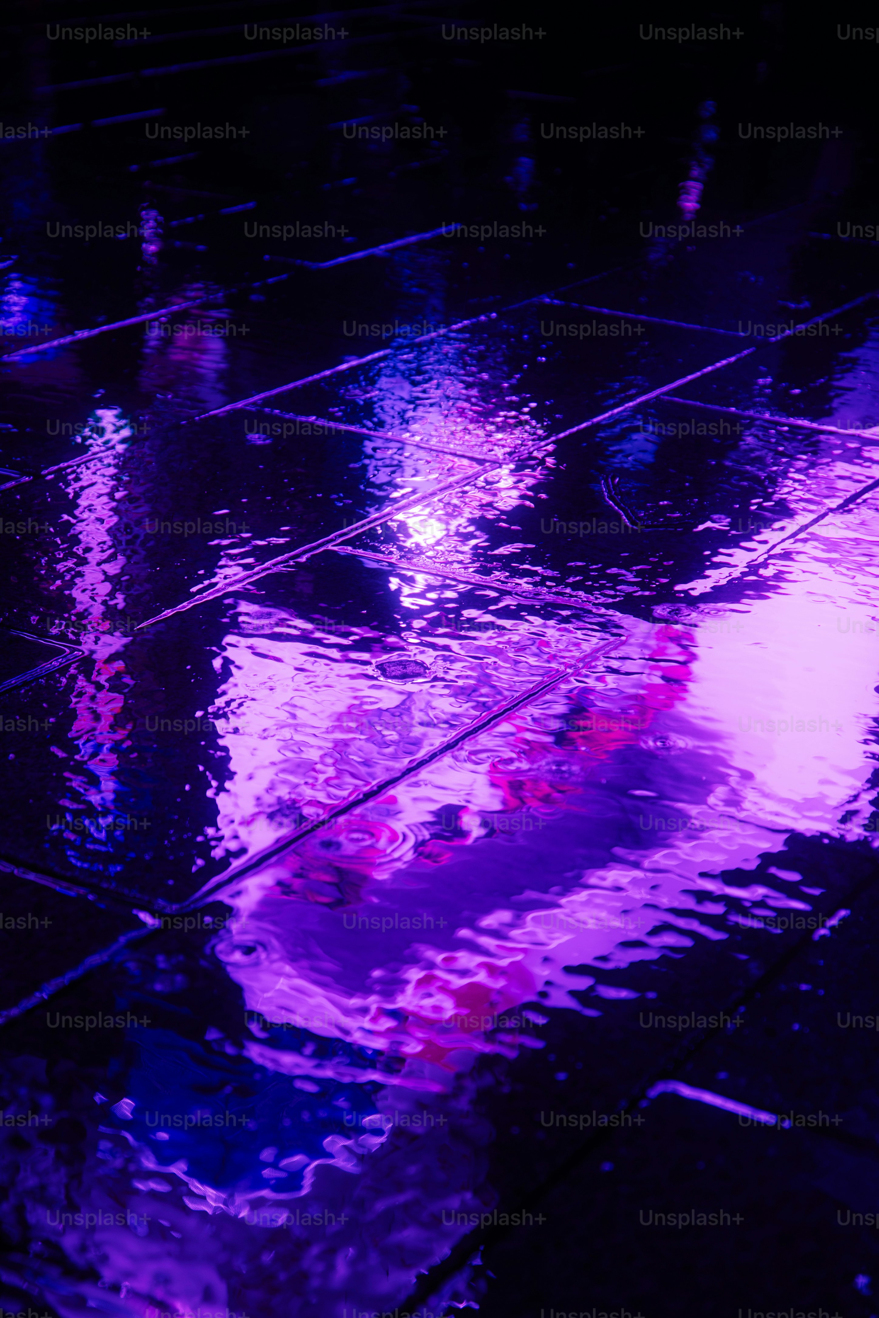 Vibrant purple and blue neon light reflecting on wet dark pavement tiles