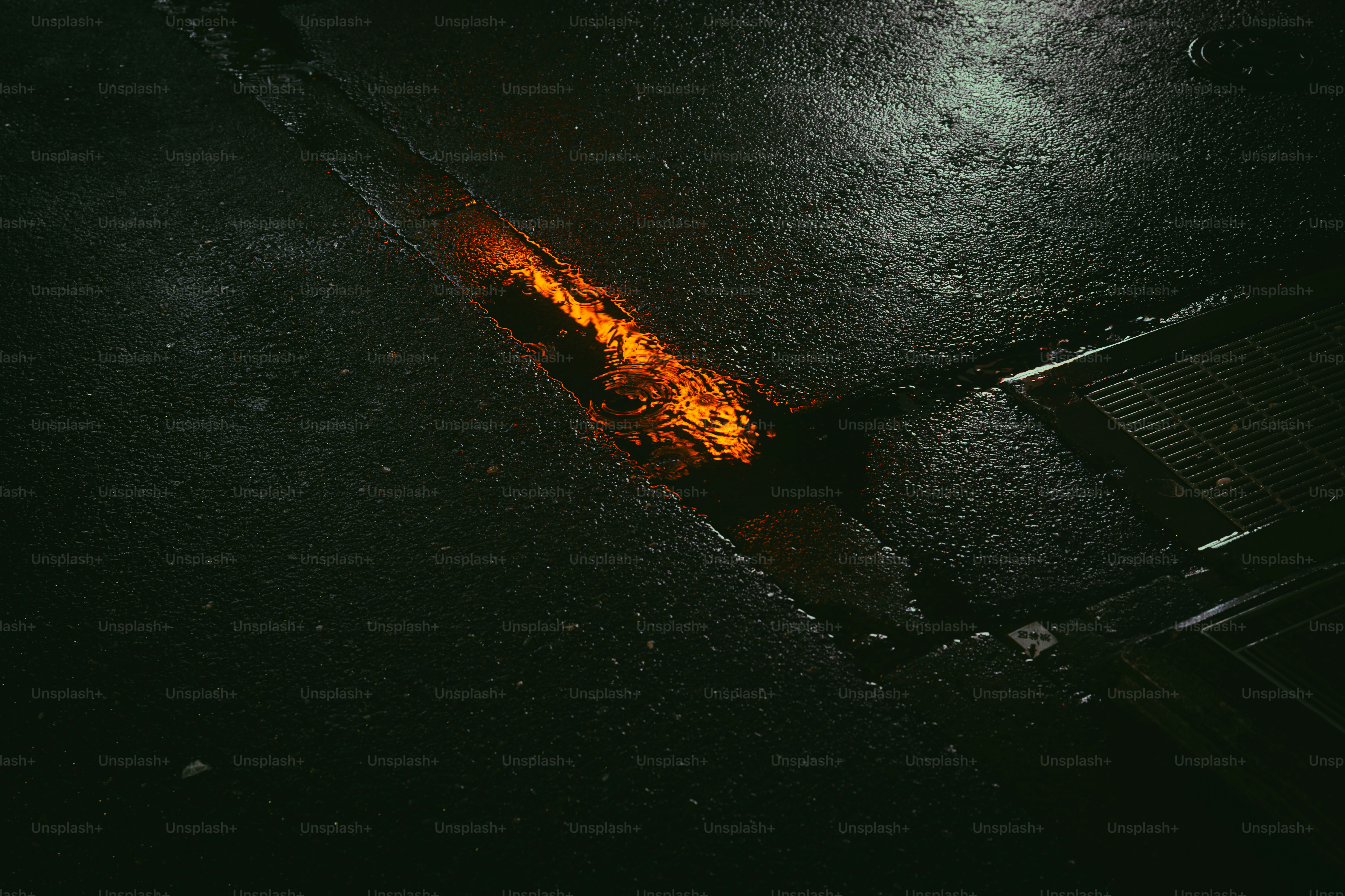 Reflet de lumière orange dans la rue mouillée - Photo sur Unsplash+