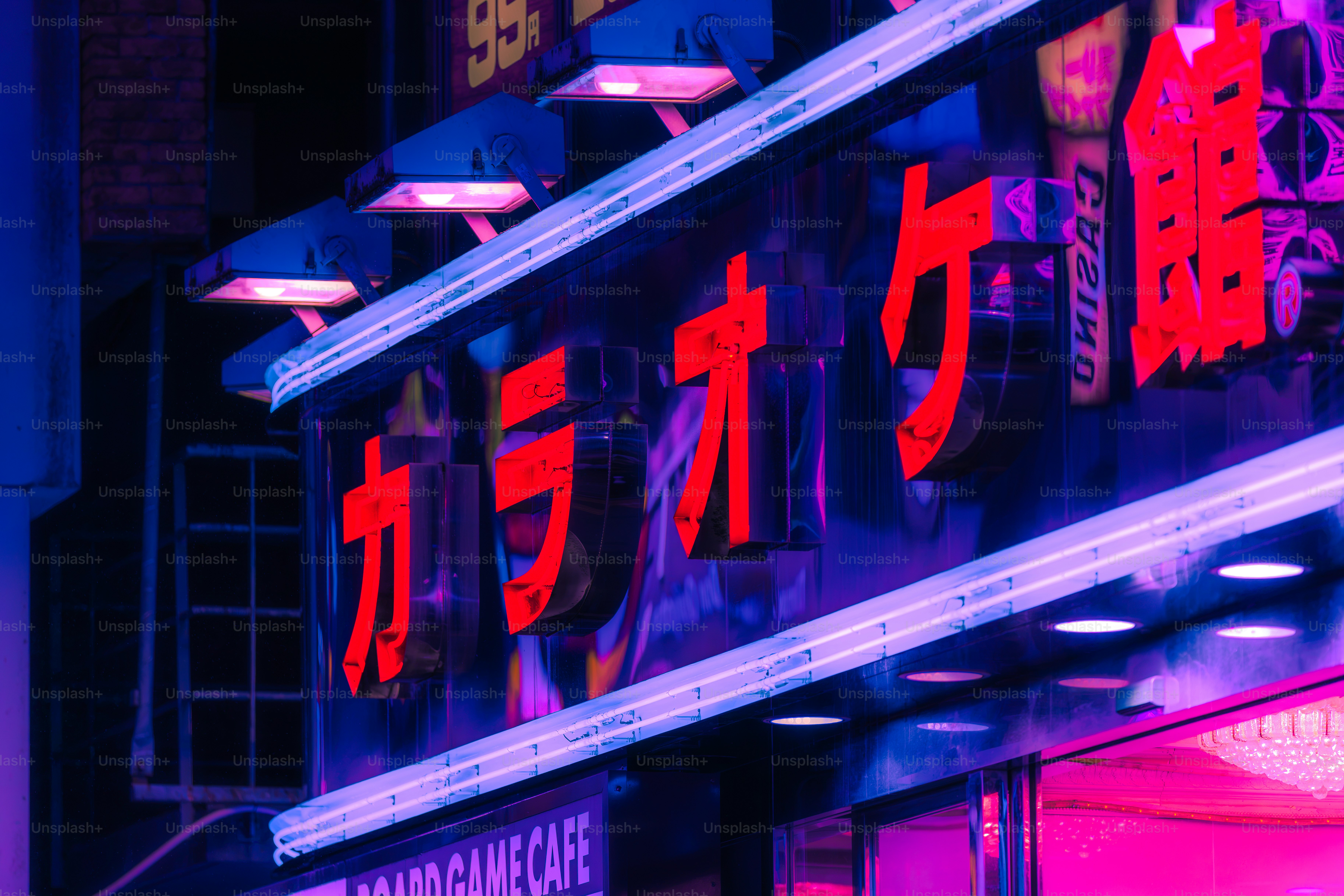 Bright red neon Japanese characters on a building facade illuminated by blue and purple lights