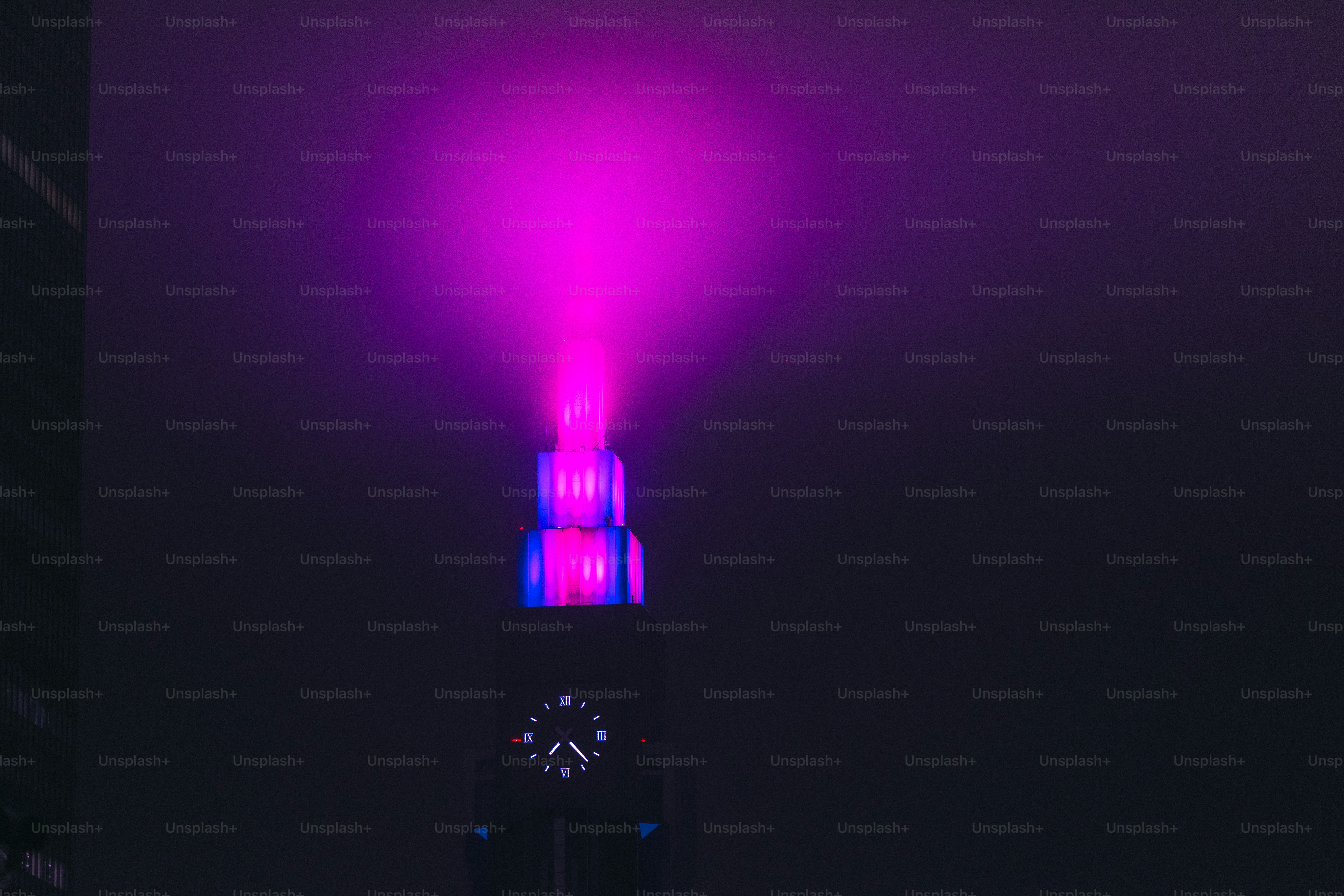 Clock tower spire with purple light - Photo on Unsplash+