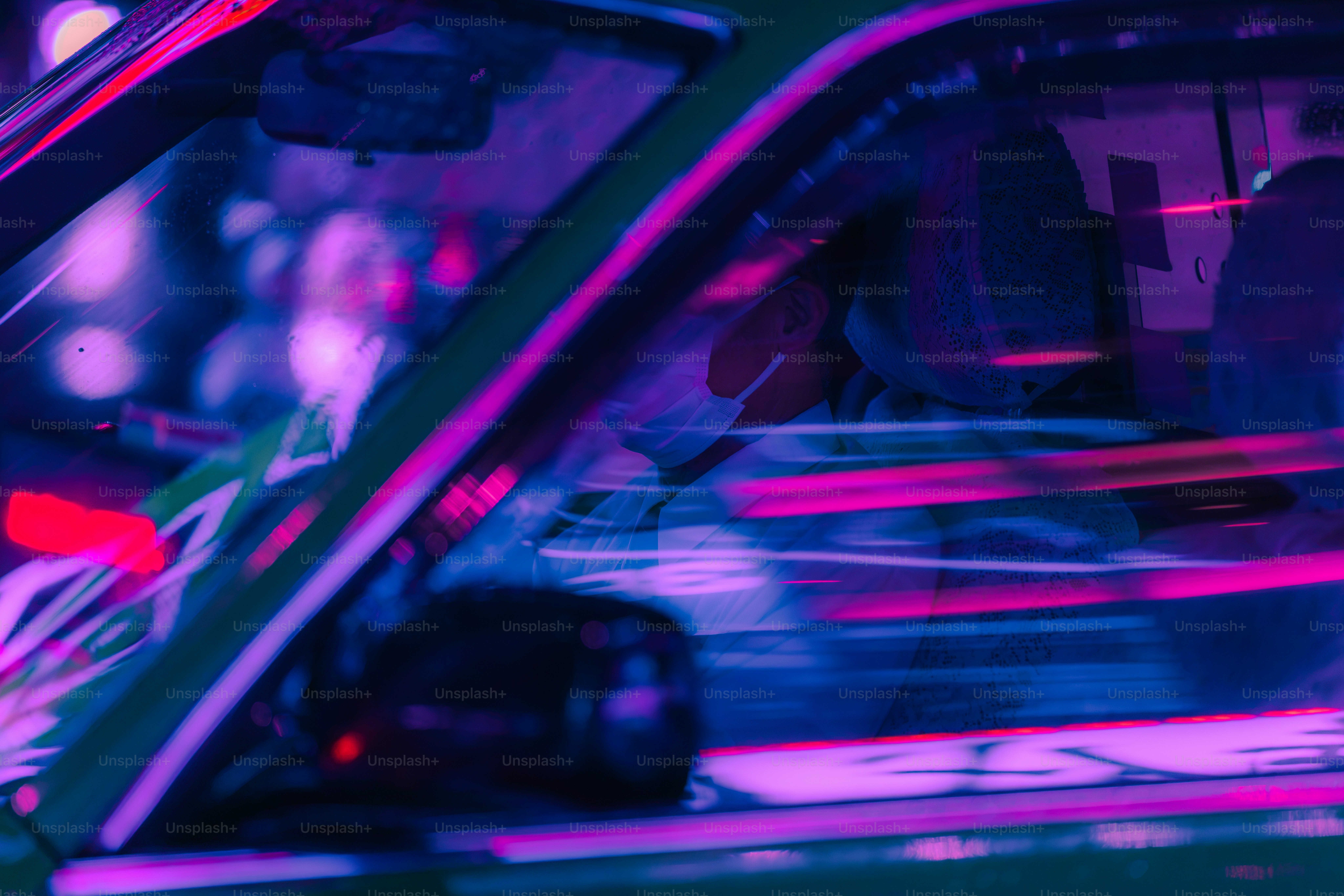 A person wearing a face mask inside a car with motion blurred neon lights