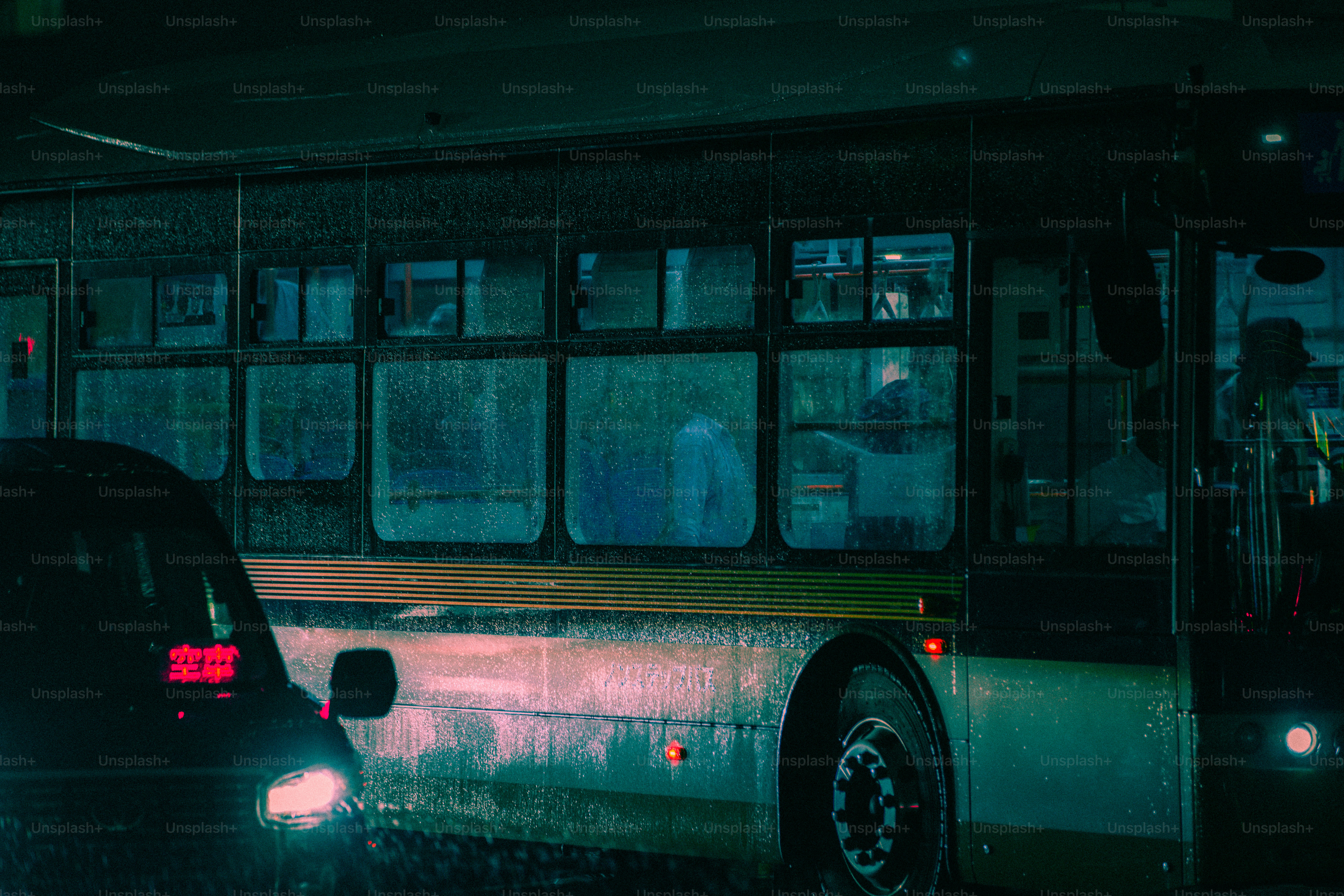 A bus on a rainy city street at night with glowing red and white lights