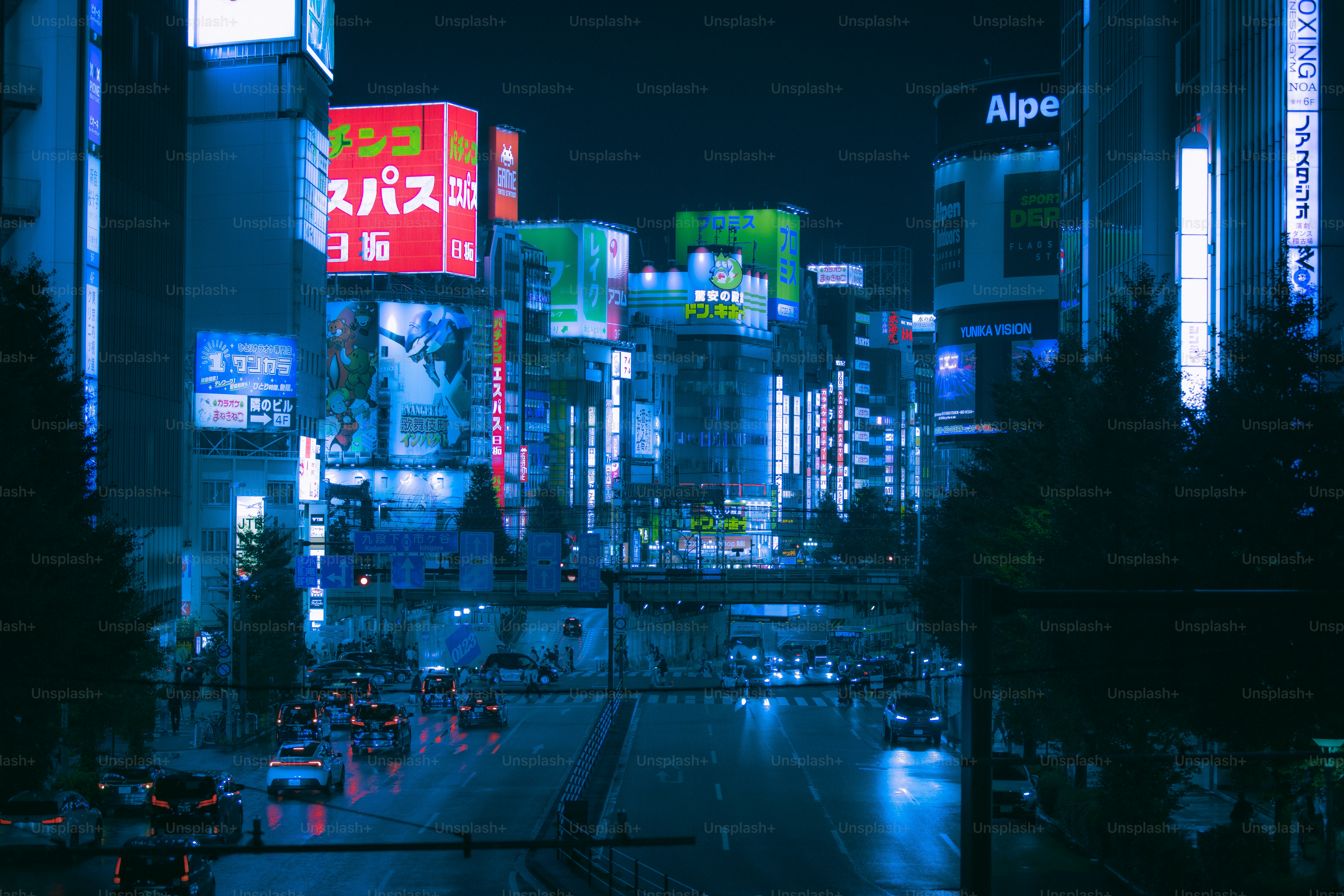 Cars driving on a street in Shinjuku City at night under glowing neon signs
