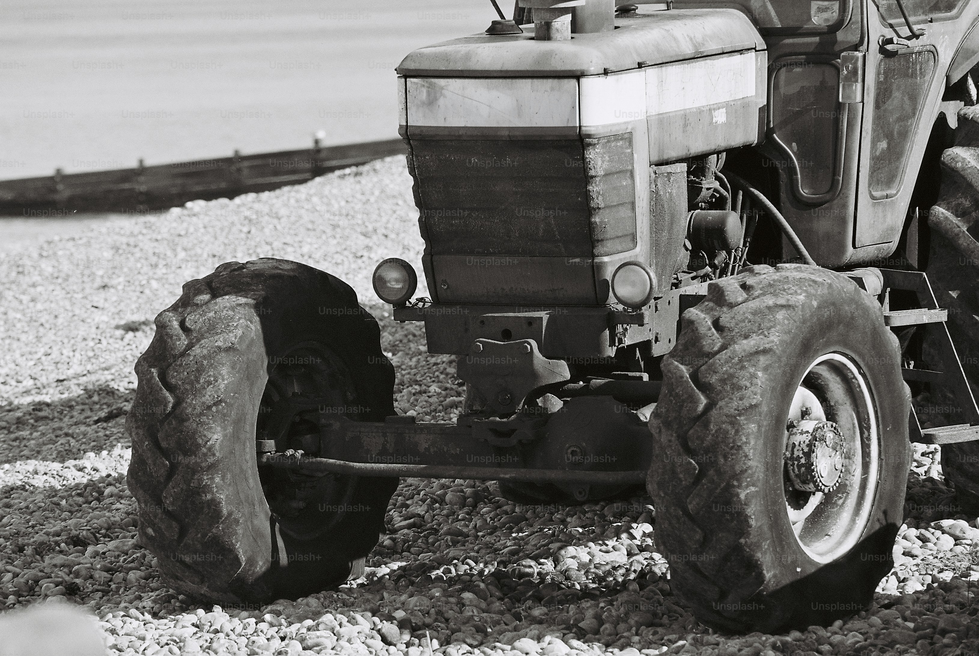 Ein Vintage-Traktor auf einem Kiesstrand mit einer Holzgrube im Hintergrund
