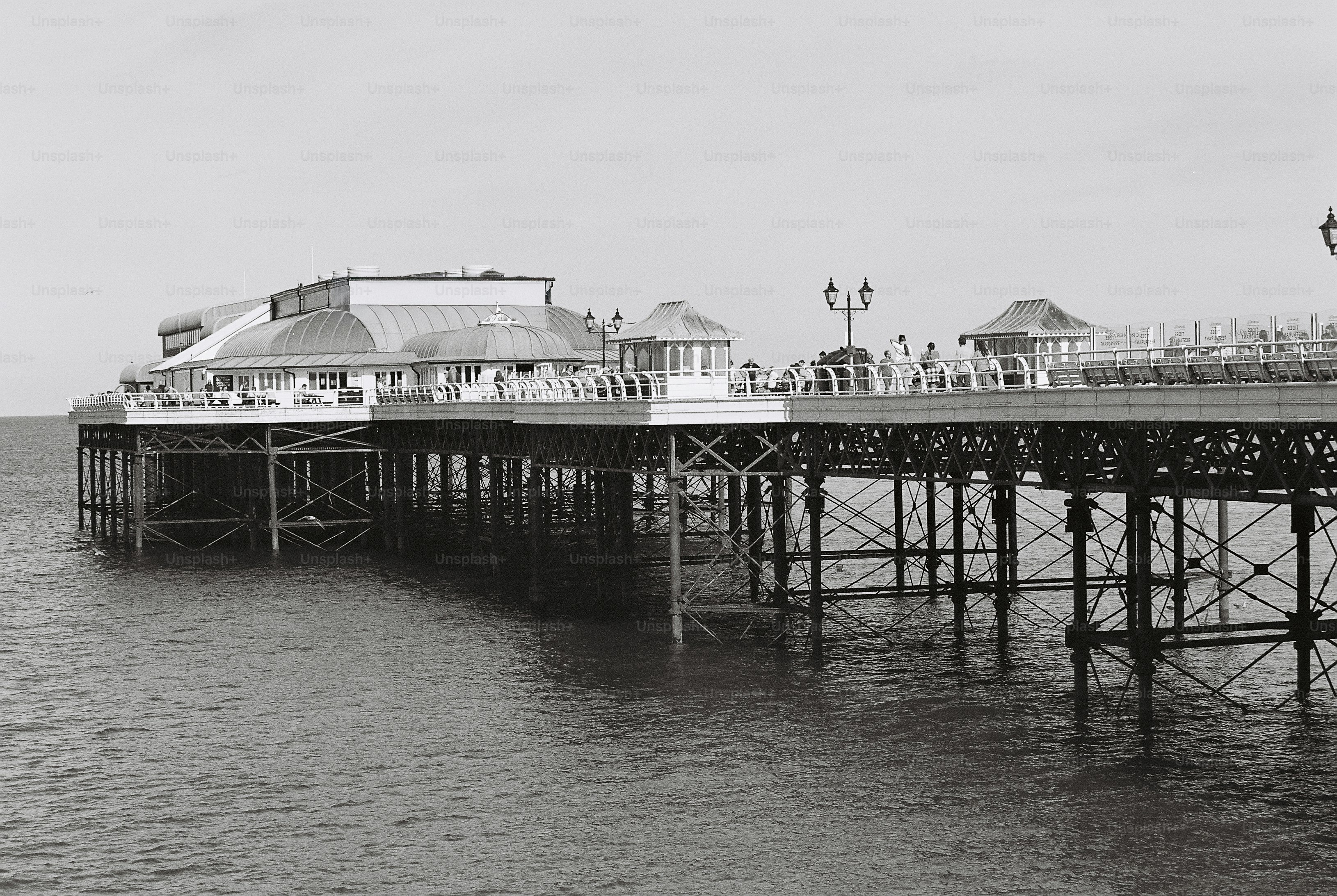 A long iron pier with a domed pavilion and kiosks extending over calm dark water