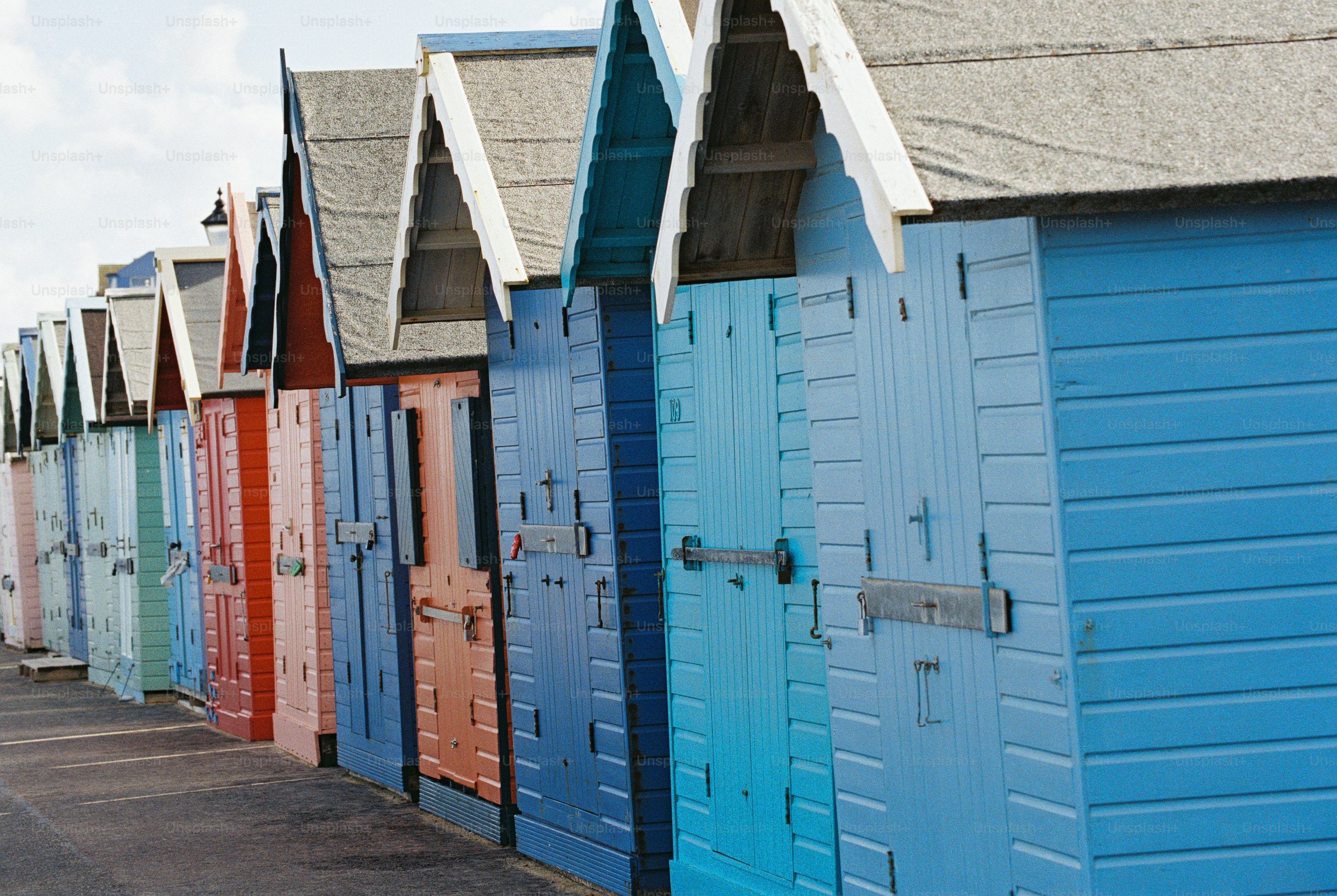 A row of colorful wooden beach huts with scalloped bargeboards along a paved promenade