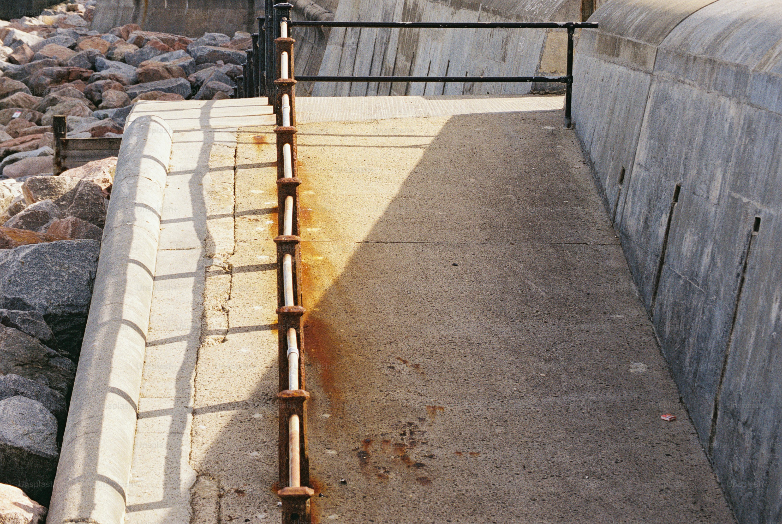 Sloping concrete walkway with rusted railing - Photo on Unsplash+