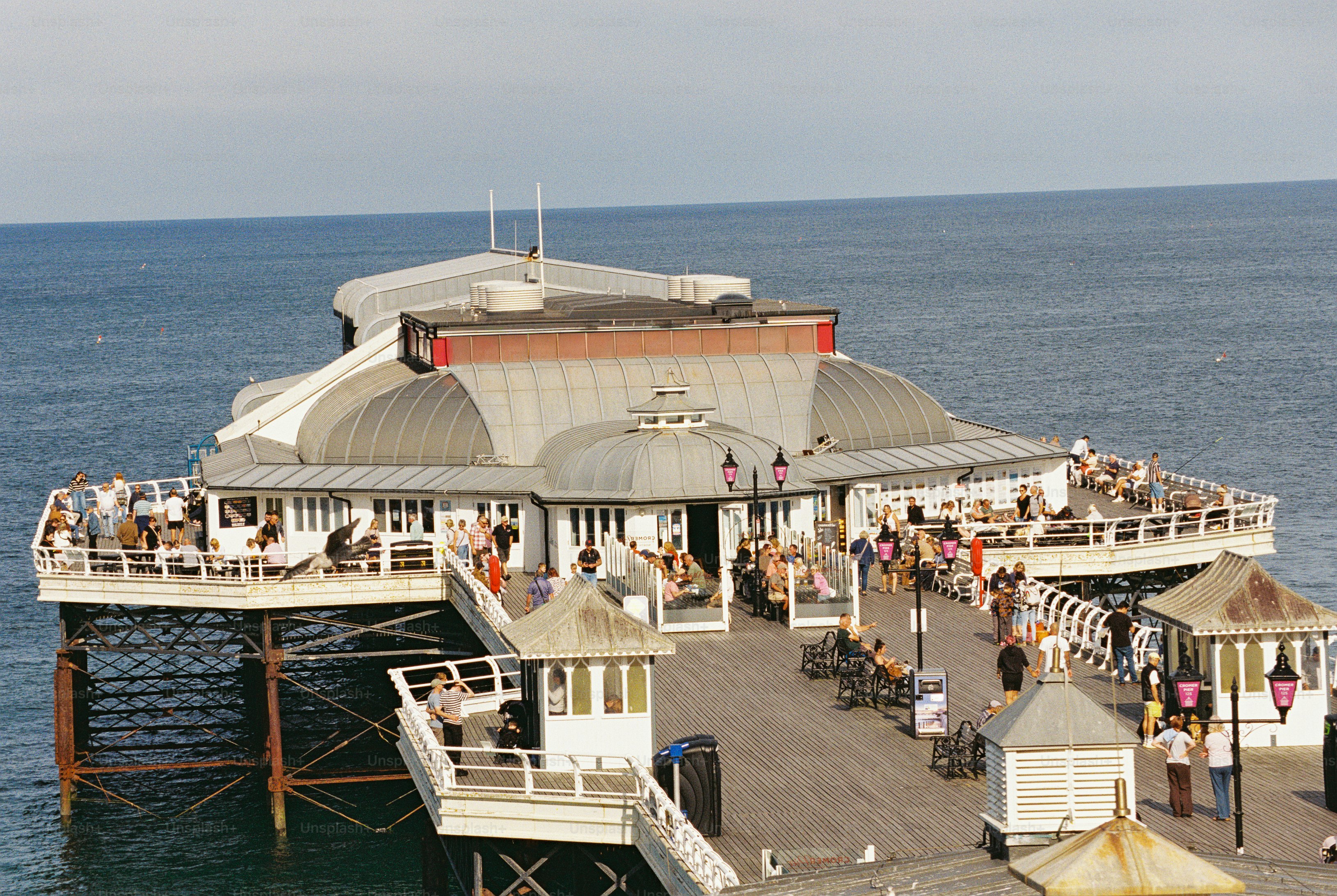 An aerial view of Cromer Pier with people on the deck above dark blue water