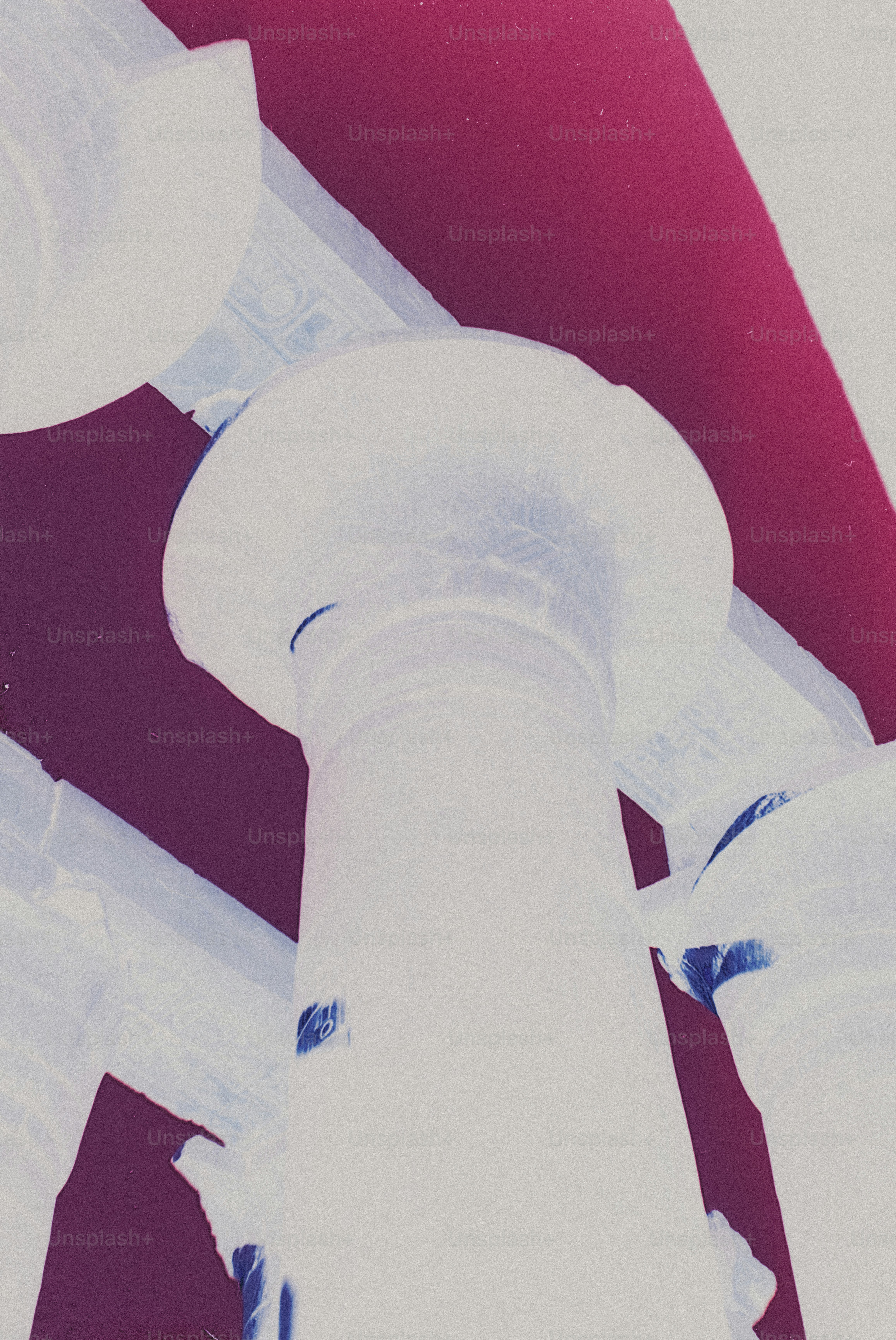 A low angle view of a white classical column against a deep magenta background