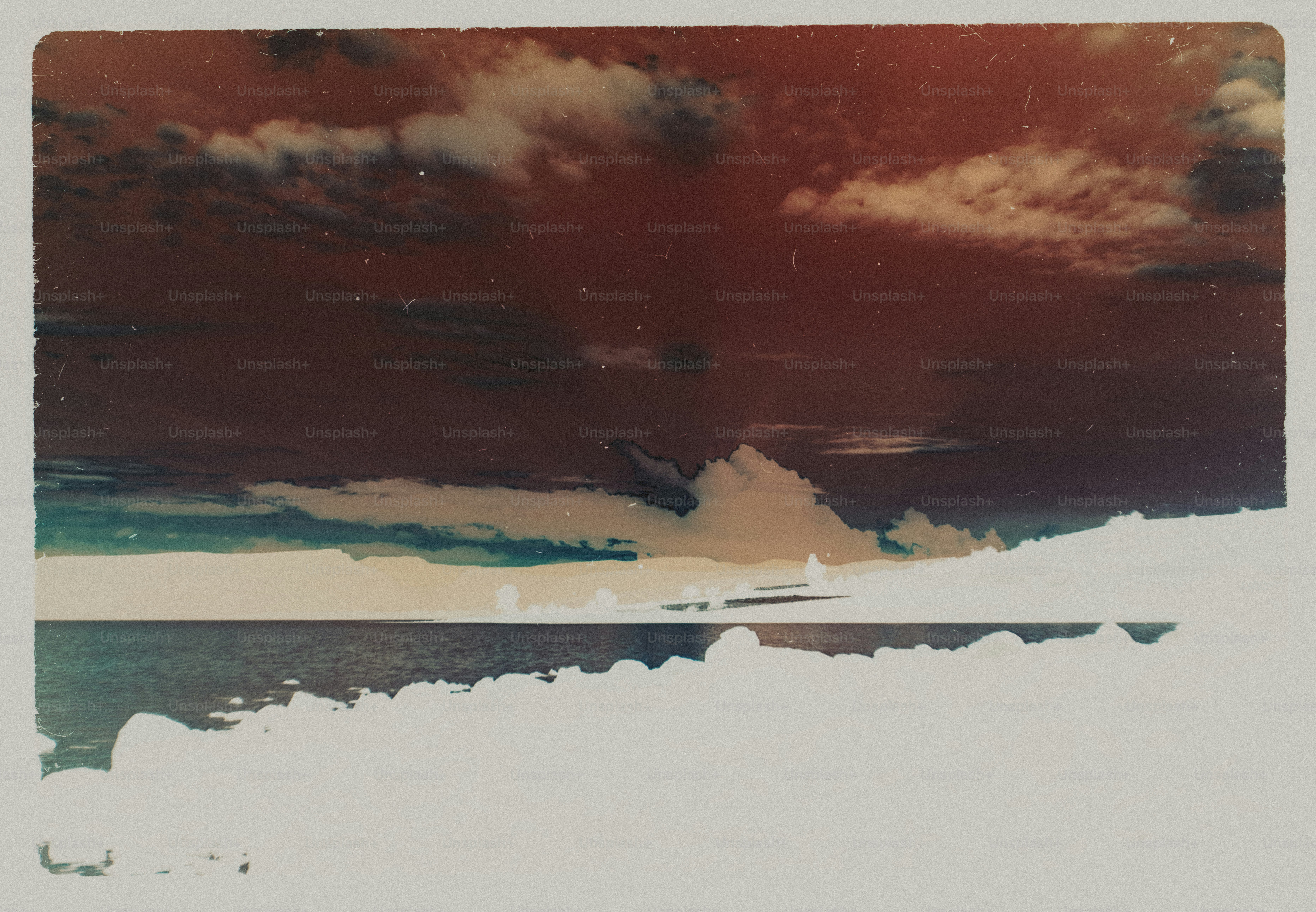 A dark inverted landscape of a sea under a cloudy sky with vintage film grain