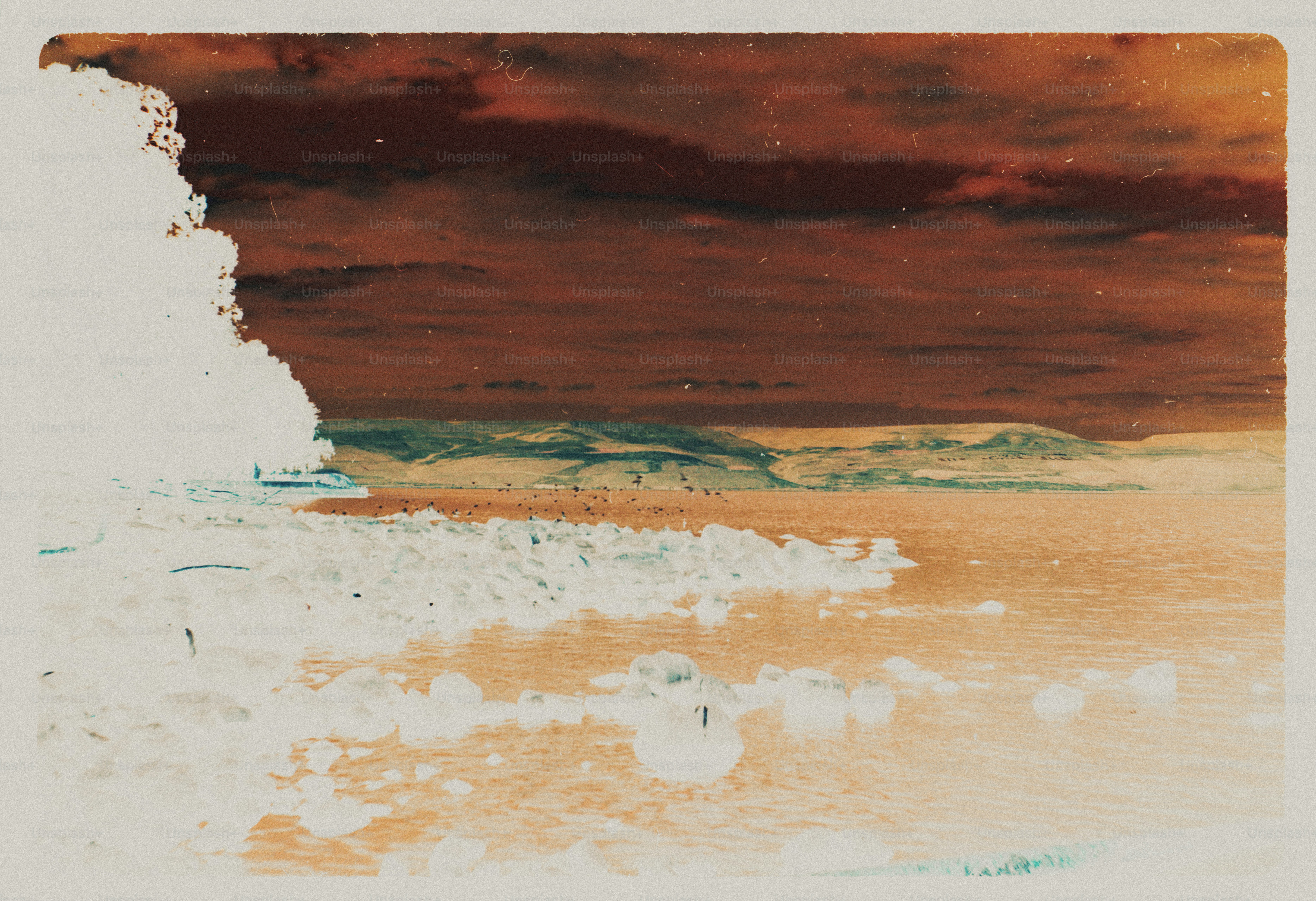 An inverted color landscape of a rocky shoreline along a calm lake with distant hills