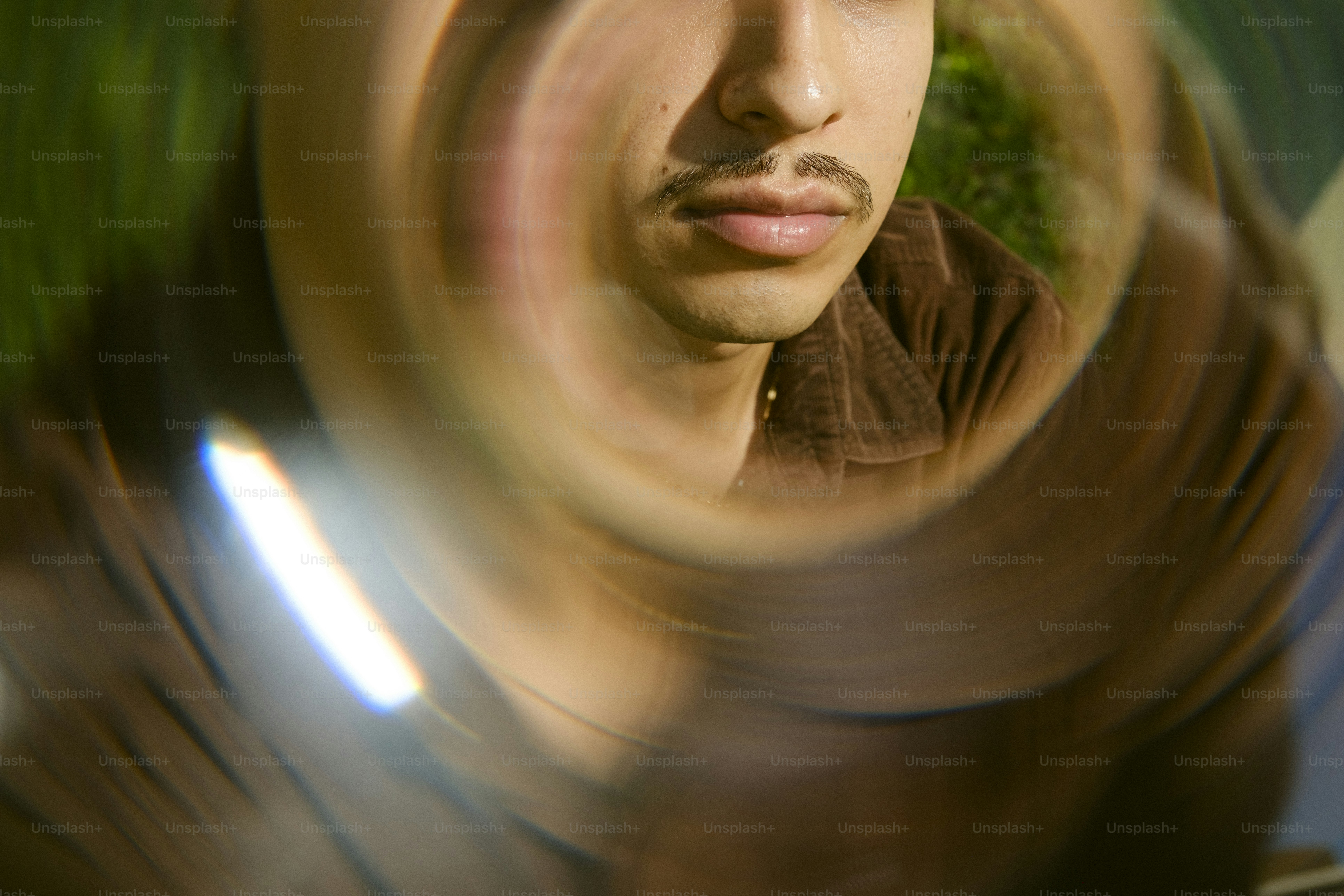 Eine Person mit Schnurrbart, gesehen durch eine kreisförmige Linse mit Lichtreflex