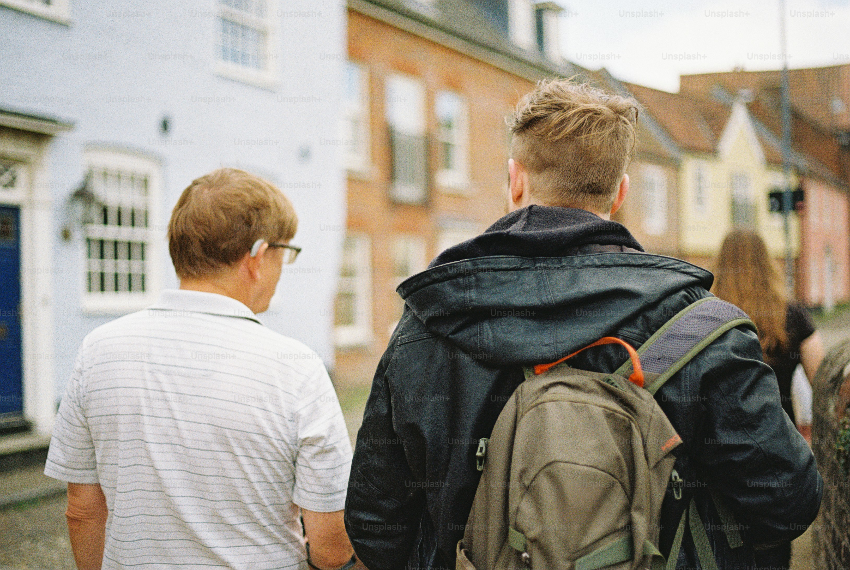 Two people walking down a street past colorful houses