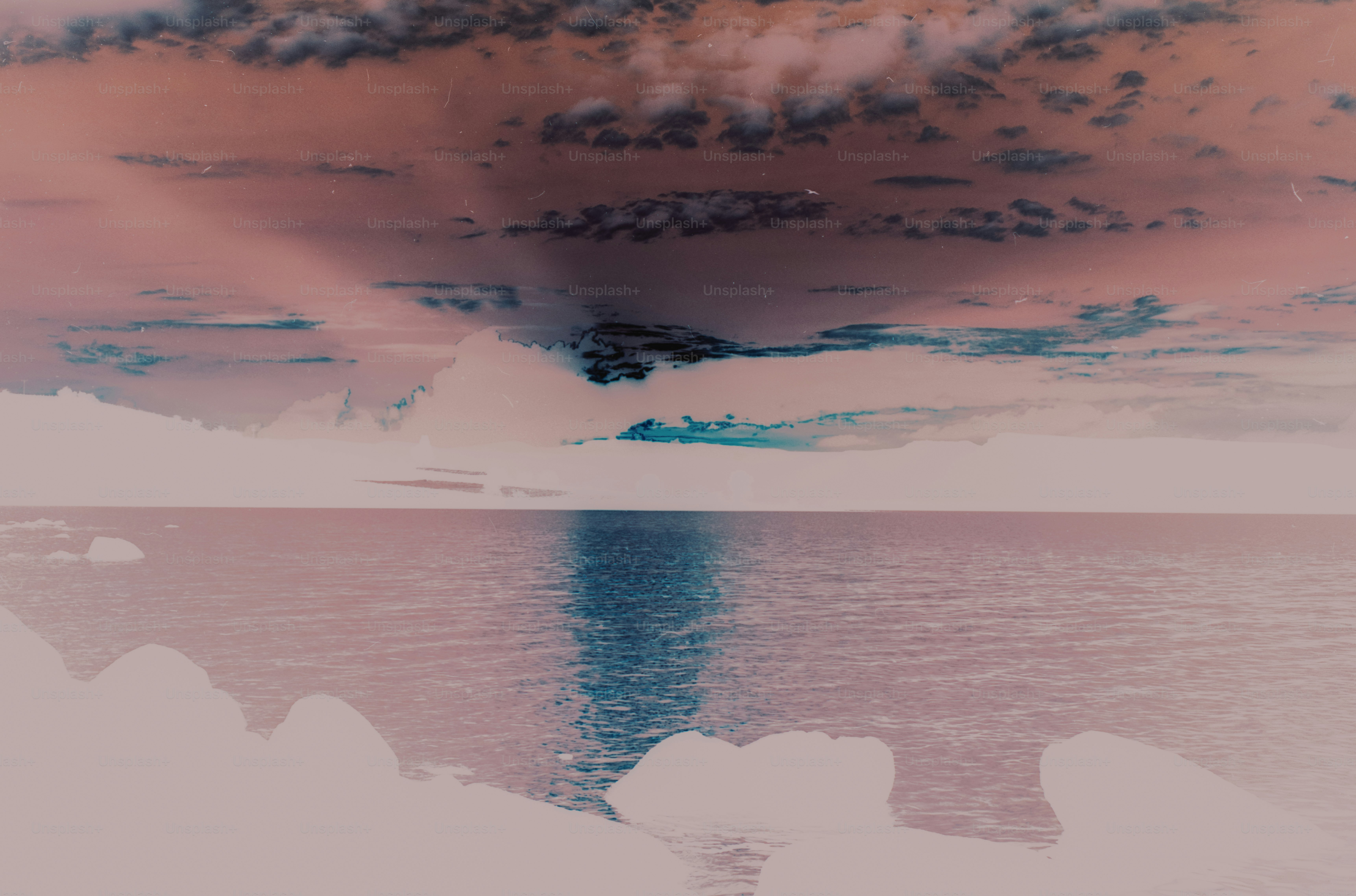 A calm body of water reflecting a dark sky with scattered clouds