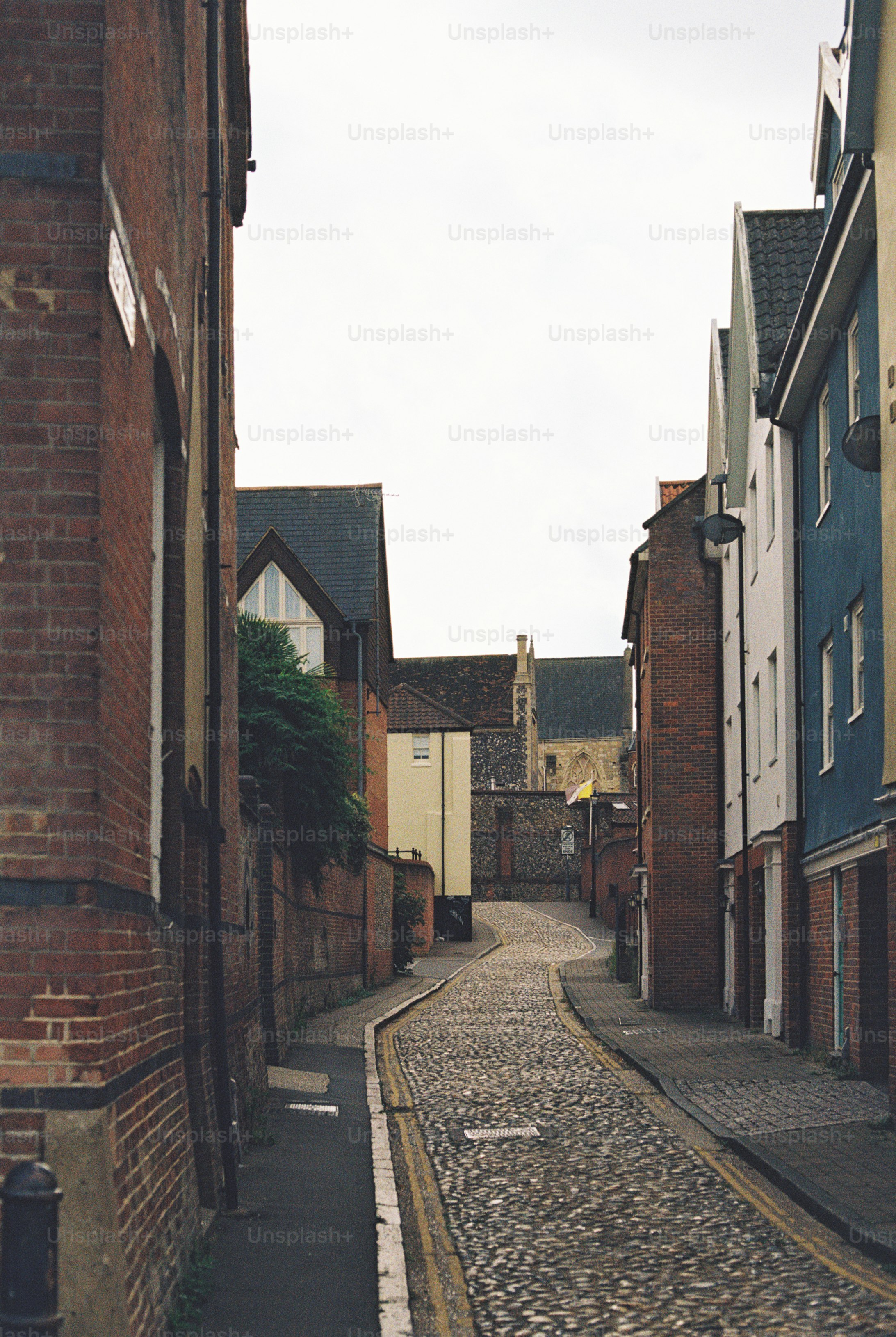 A narrow cobblestone street winding between historic brick and timber-framed buildings