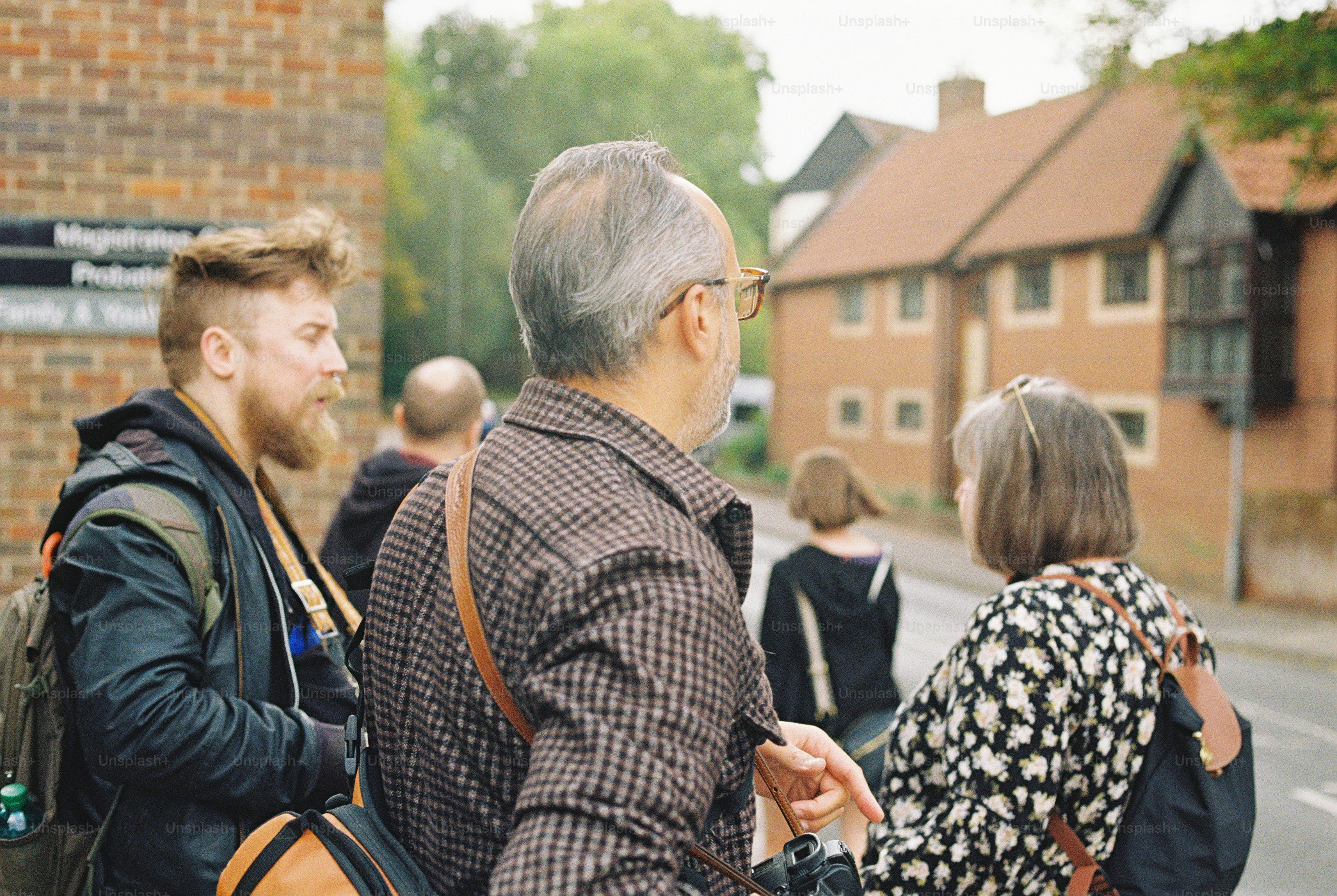A group of people standing on a street near a brick building